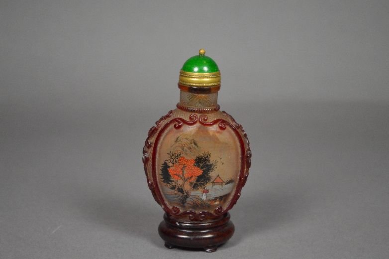 Reverse painting on carved Peking glass snuff b: Peking glass snuff bottle, early 20 th c. reversed painting on Peking glass, an red borders and floral designs on the side, signed by Zhou leyuan. With wood stand. from a private collector Potsdam. VT