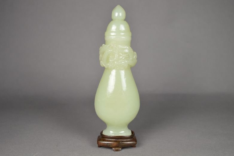 Carved jade vase: jade vase, 19 th c. detailed carved dragon pattern on neck, with wood stand. 5 1/4" x 2"