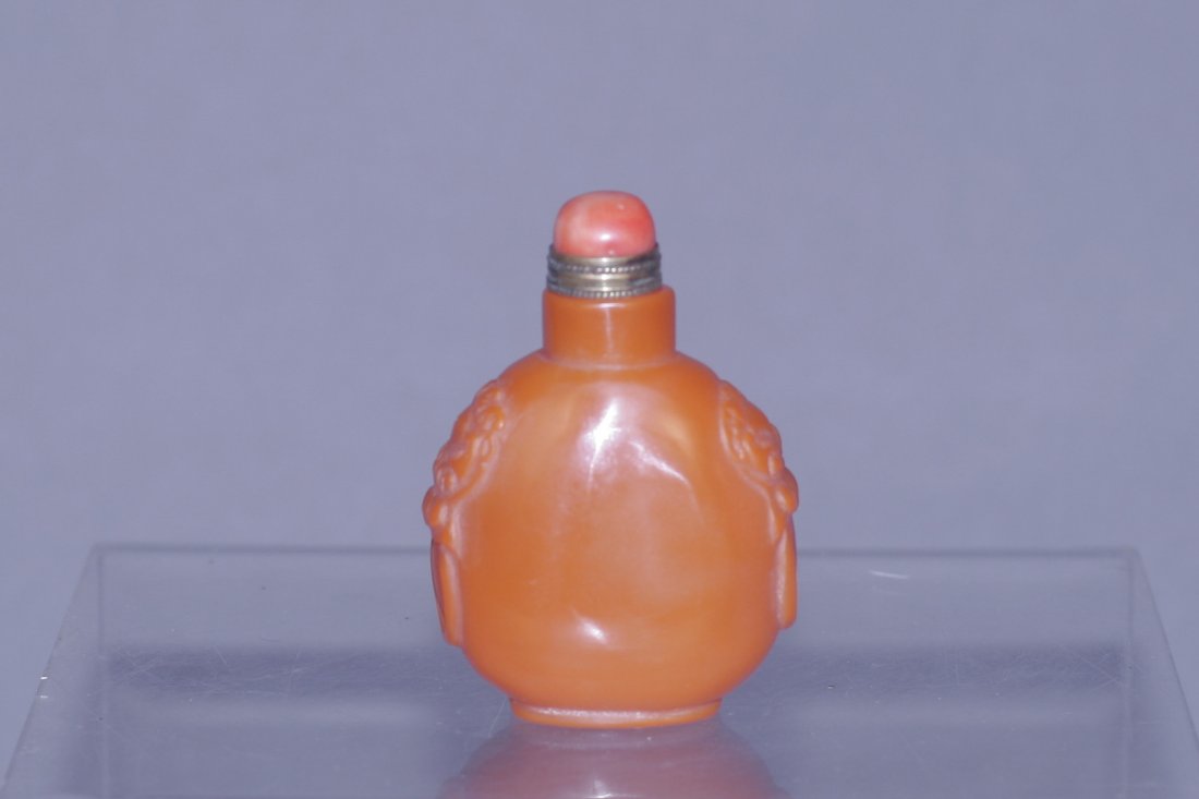 carved red soapstone snuff bottle: red soapstone snuff bottle. China, decorated foo-lion head pattern on the shoulders. 3"