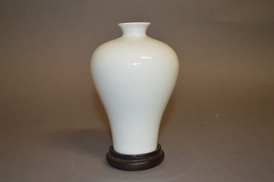 White Glazed Porcelain Mei Vase: Mei Vase, China, Ming Dynasty or later, Mei shaped vase, with carved flying dragon pattern under glaze Carved Chinese character mark on base. With hard wood shand. 5 1/2”