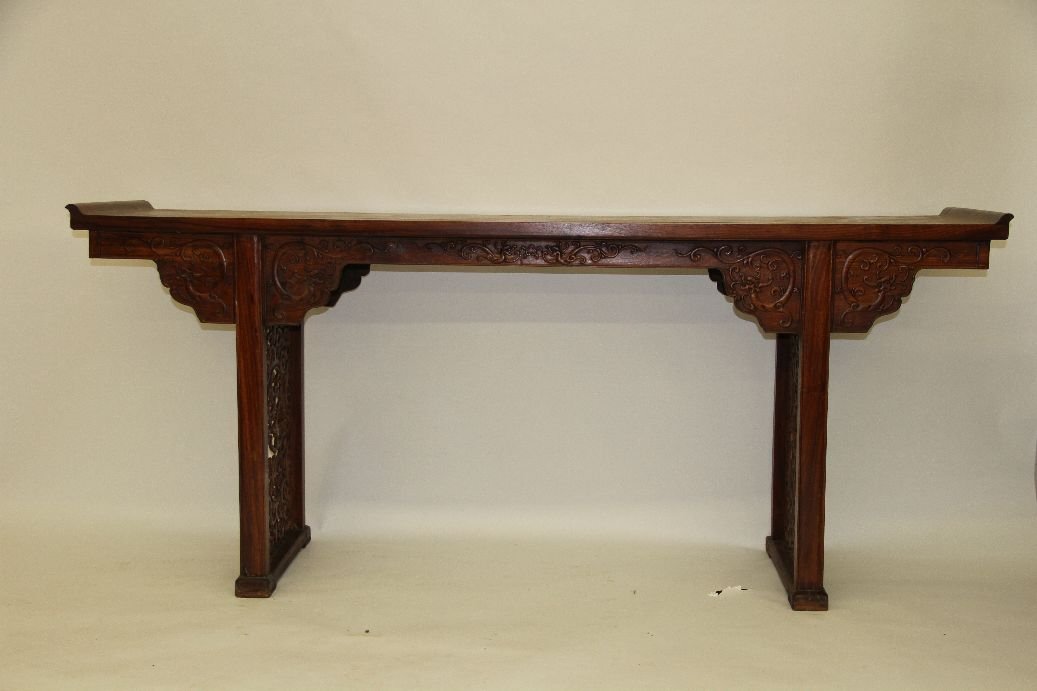 Huanghuali Altar Table: Chinese carved huanghuali altar table, the rectangular top with everted ends surmounting a shaped apron, adorned with archaistic dragons in profile, including a pair of confronting dragons flanking a 