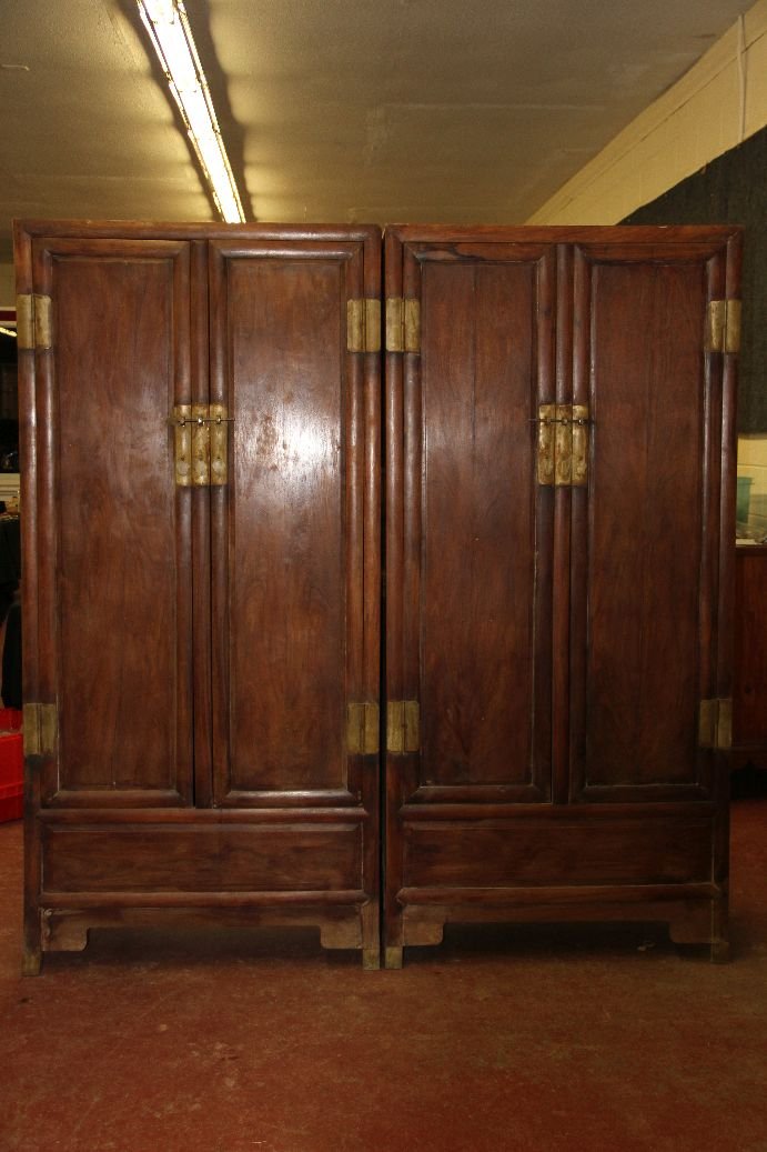 Pair Larage Huanghuali Cabinets: Pair of tall, Chinese Ming-style huanghuali wood cabinets; each of simple sloped form, raised on four legs; each side opening to reveal two drawers inside