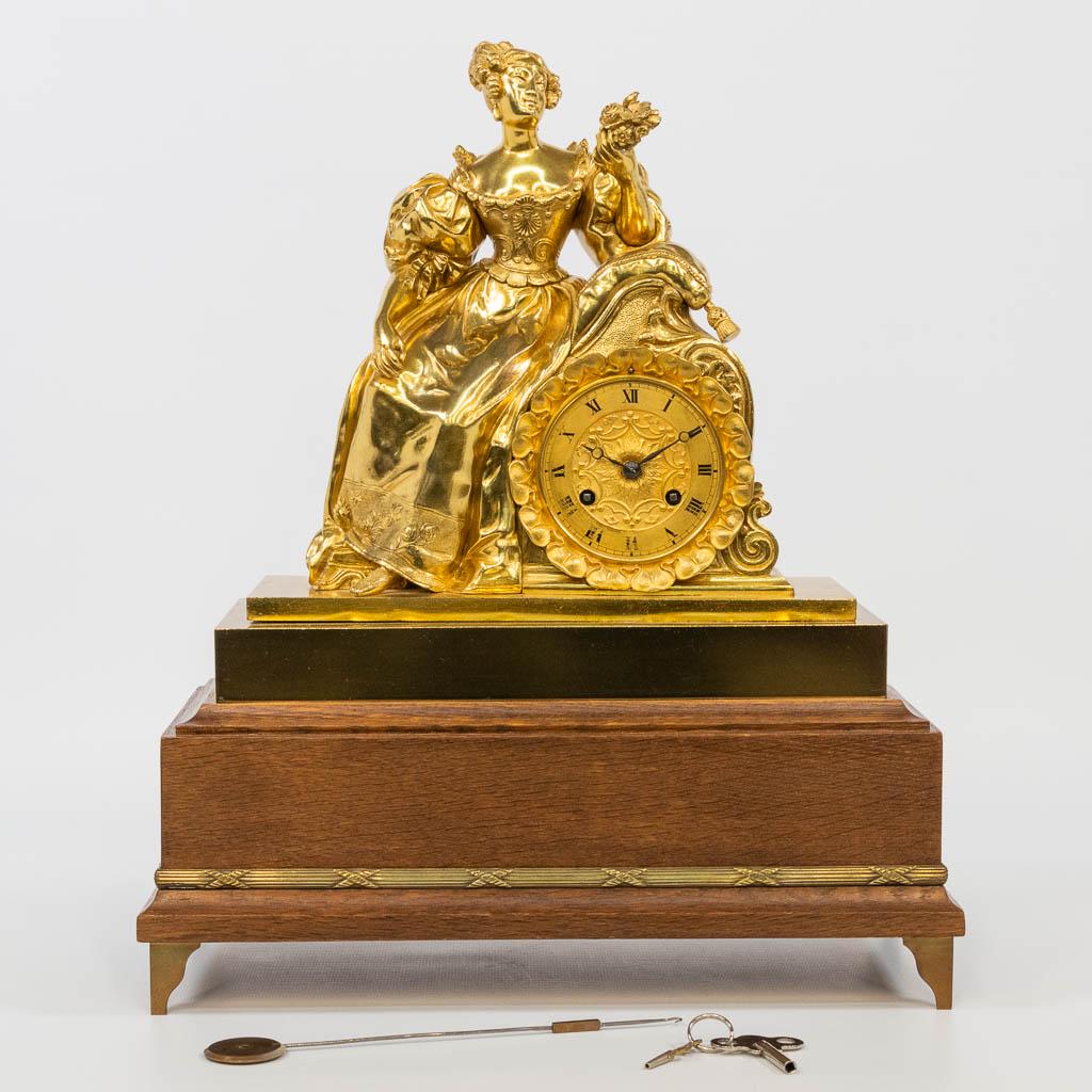 An ormolu gilt table clock on a wood base, with a (1 of 15)