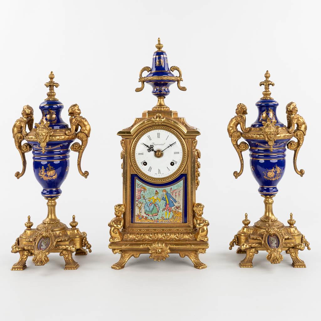 A three-piece mantle garniture clock made of bronze and: A three-piece mantle garniture clock made of bronze and porcelain and marked Imperial. 20th centrury. Height sidepieces: 36 cm. (13 x 18 x 43 cm)