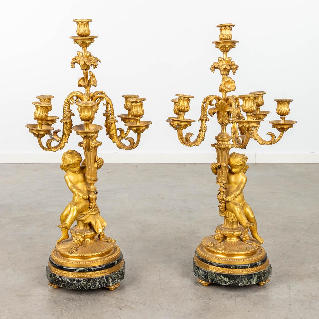 A pair of candelabra made of gilt bronze on a marble stand and decorated with putti. 19th C.  (L:28 (1 of 18)