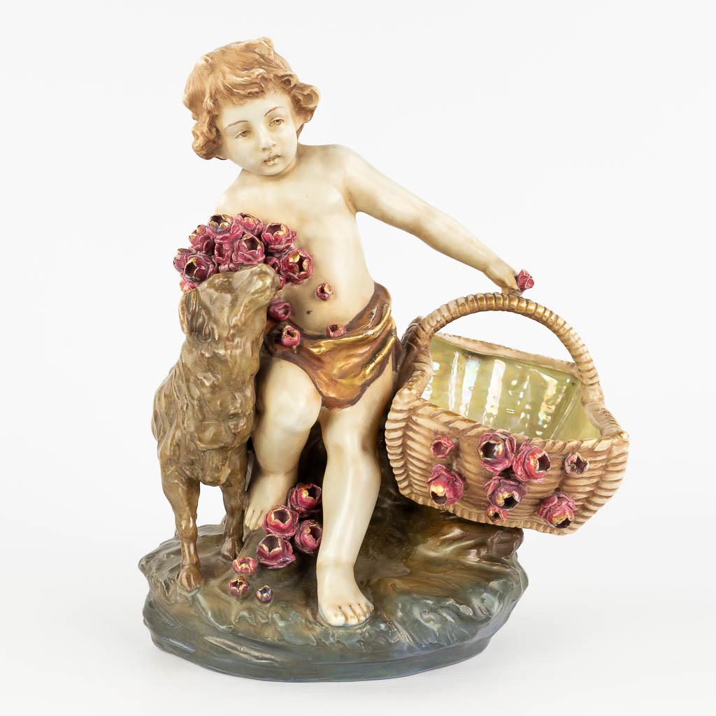 Amphora Austria, 'Child with a basket and sheep' made of glazed faience. (L: 18 x W: 24 x H: 29,5: Amphora Austria, 'Child with a basket and sheep' made of glazed faience. Marked on the base. 