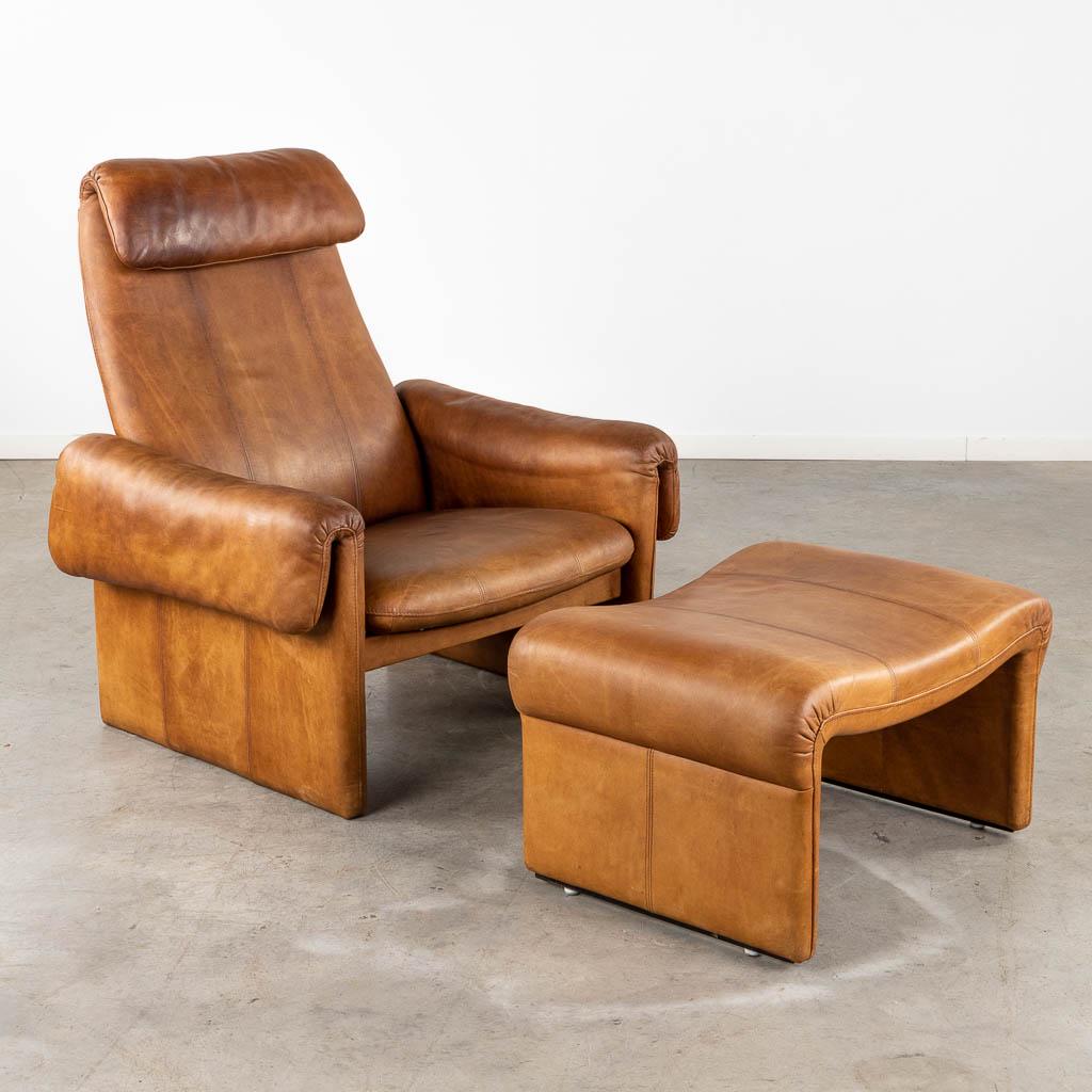 A mid-century lounge chair with ottoman, leather. (D:86 x W:90 x H:96 cm): A mid-century lounge and relax chair with ottoman, leather. In the style of De Sede. Dimensions:(D:86 x W:90 x H:96 cm)