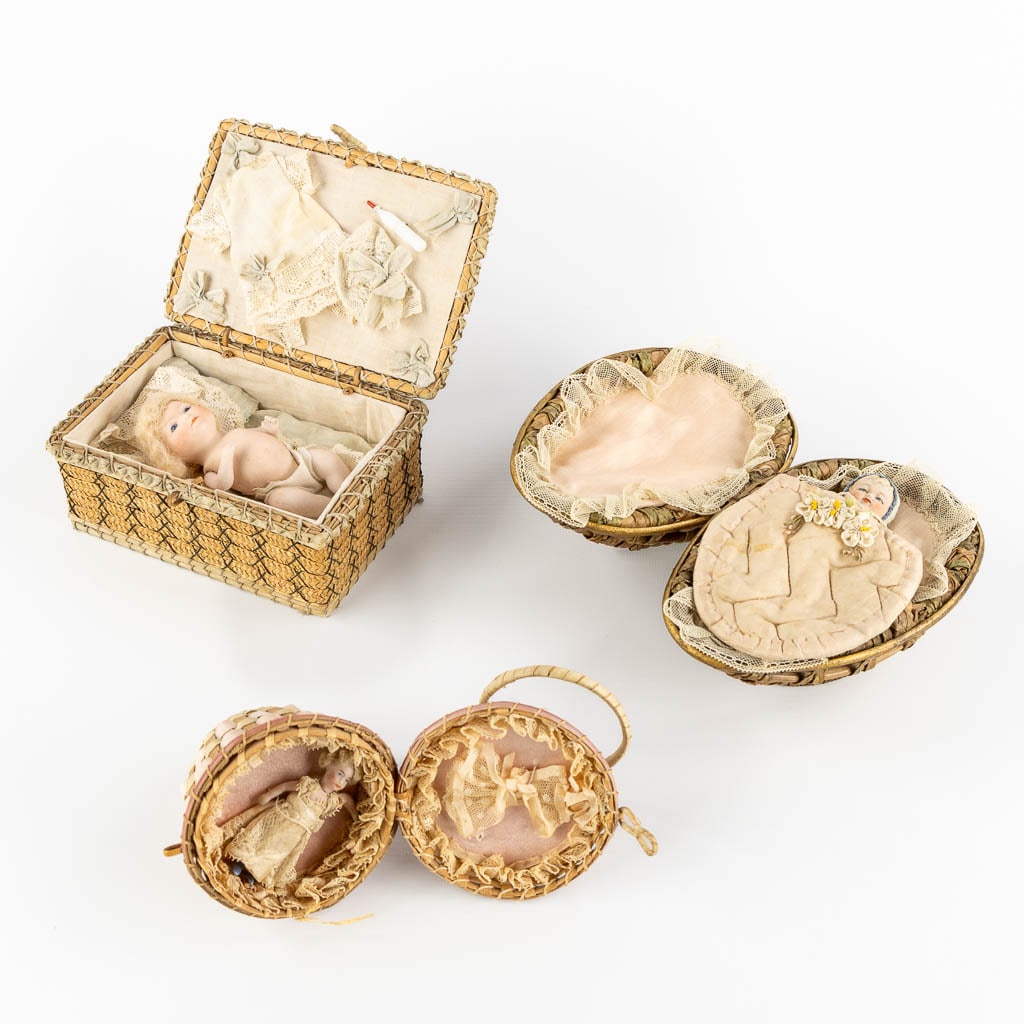 Three antique dolls, stored in a woven basket. (L:11,5 x W:17 x H:7 cm): Three antique dolls, stored in a woven basket. One signed O.S. Putnam, 1922. Dimensions: (L:11,5 x W:17 x H:7 cm)