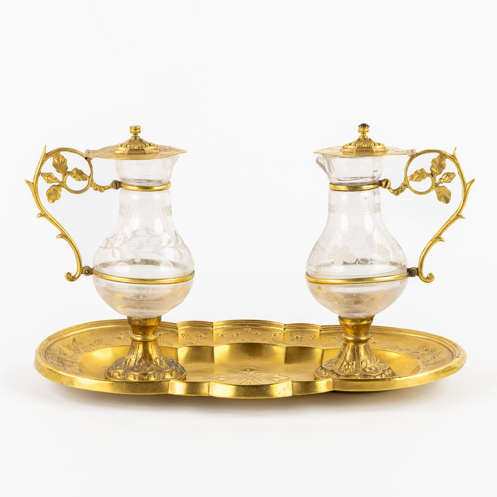 A pair of water and wine cruets, gothic revival, gilded copper and glass.: A pair of water and wine cruets, gothic revival, gilded copper and glass. Glass engraved with grape vines and cattail. Lids are finished with a cabochon.
