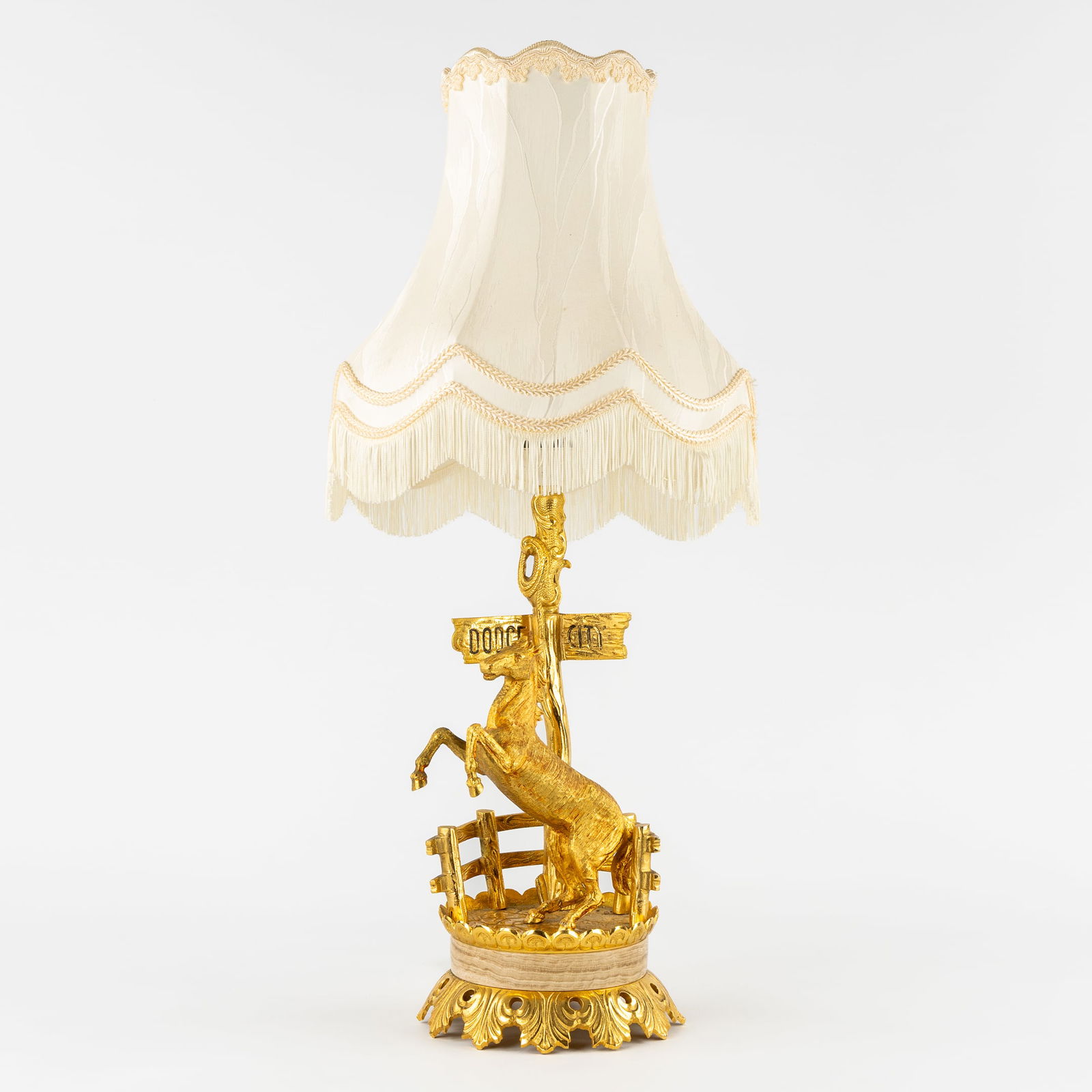 A Table lamp 'Dodge City', with a Rearing Horse, Gilded Bronze, probably Deknudt, Circa 1950.: A Table lamp 'Dodge City', with a Rearing Horse, Gilded Bronze, probably Deknudt, Circa 1950. Gilded bronze.Table lamp, decorated with a rearing horse in front of the 'Dodge City' town sign.Probably