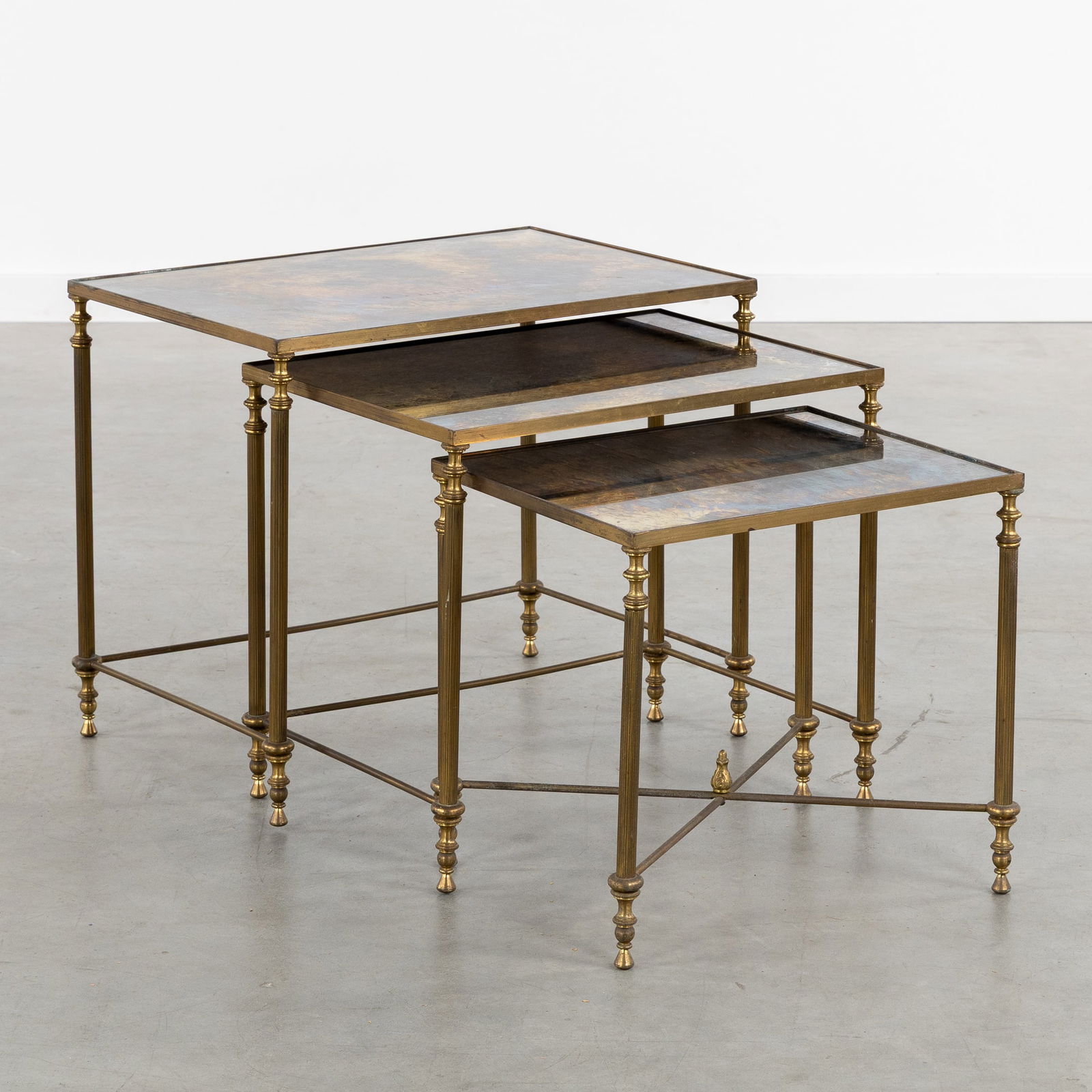 A Set of Three Nesting Tables with Iridescent Tinted Mirror Glass, in the Style of Maison Janssen: A Set of Three Nesting Tables with Iridescent Tinted Mirror Glass, in the Style of Maison Janssen and Maison Baguès. Circa 1960. Brass and glass.Three rectangular nesting side tables.Mirror glass