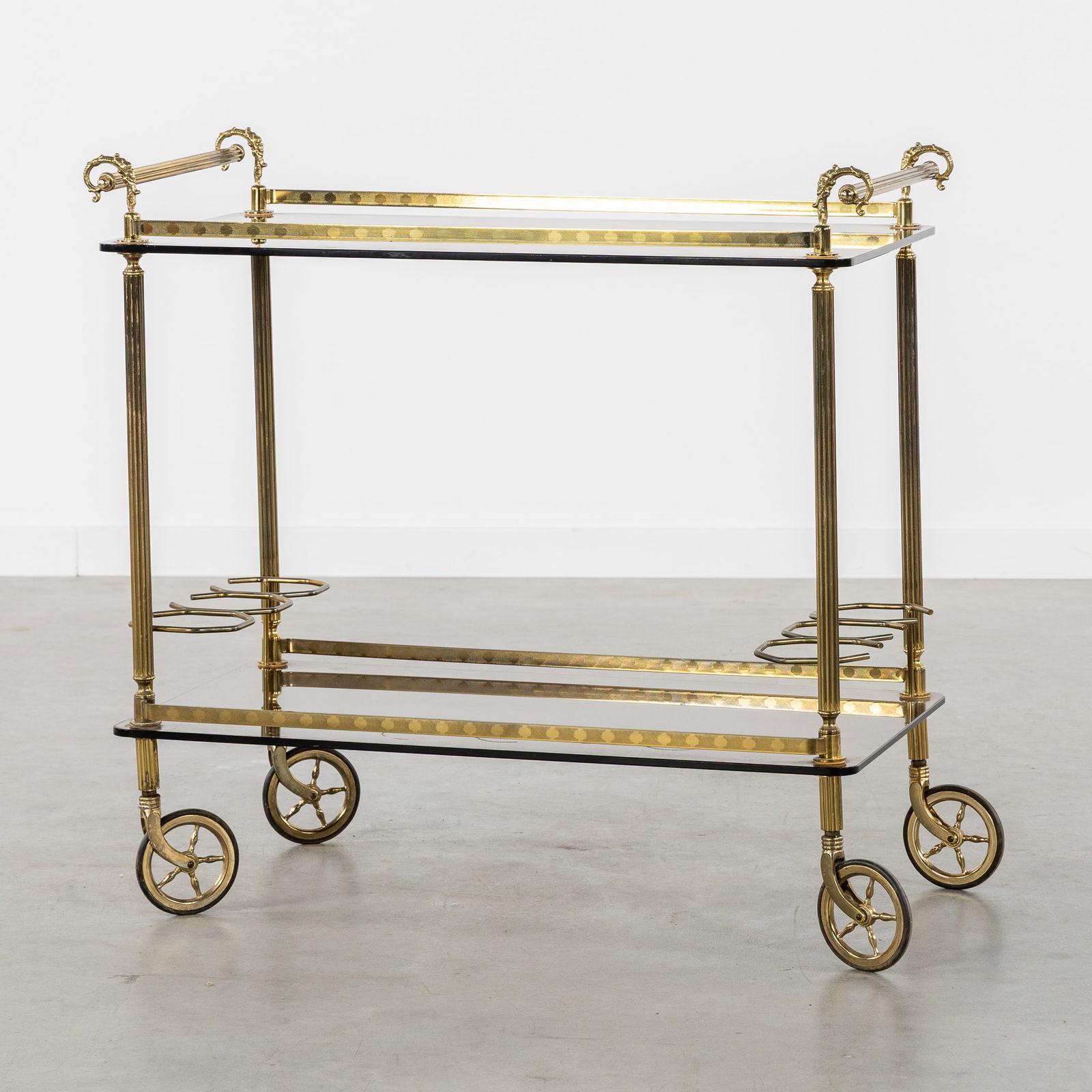 A Serving Trolley or Bar Cart, Brass and Tinted Glass, Hollywood Regency Style, circa 1980.: A Serving Trolley or Bar Cart, Brass and Tinted Glass, Hollywood Regency Style, circa 1980. Gilded brass/bronze and tinted glass.Serving trolley or bar cart with two bottle holders (for a total of six