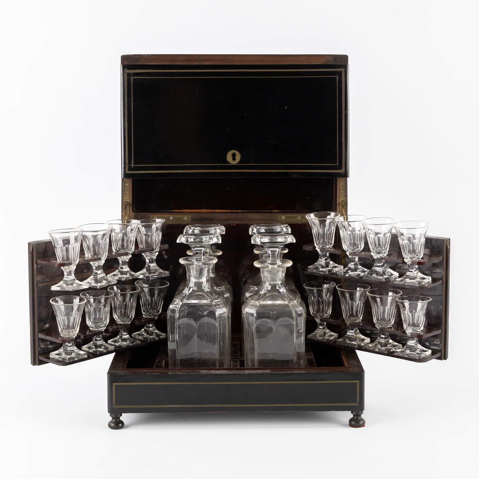 An Antique 'Cave à Liqueur' or 'Tantalus', a Liqueur Cabinet with 4 Decanters and Glasses. Napoleon: An Antique 'Cave à Liqueur' or 'Tantalus', a Liqueur Cabinet with 4 Decanters and Glasses. Napoleon III period, 19th century. Ebonized wooden liqueur cabinet or tantalus with brass inlay.4 decanters