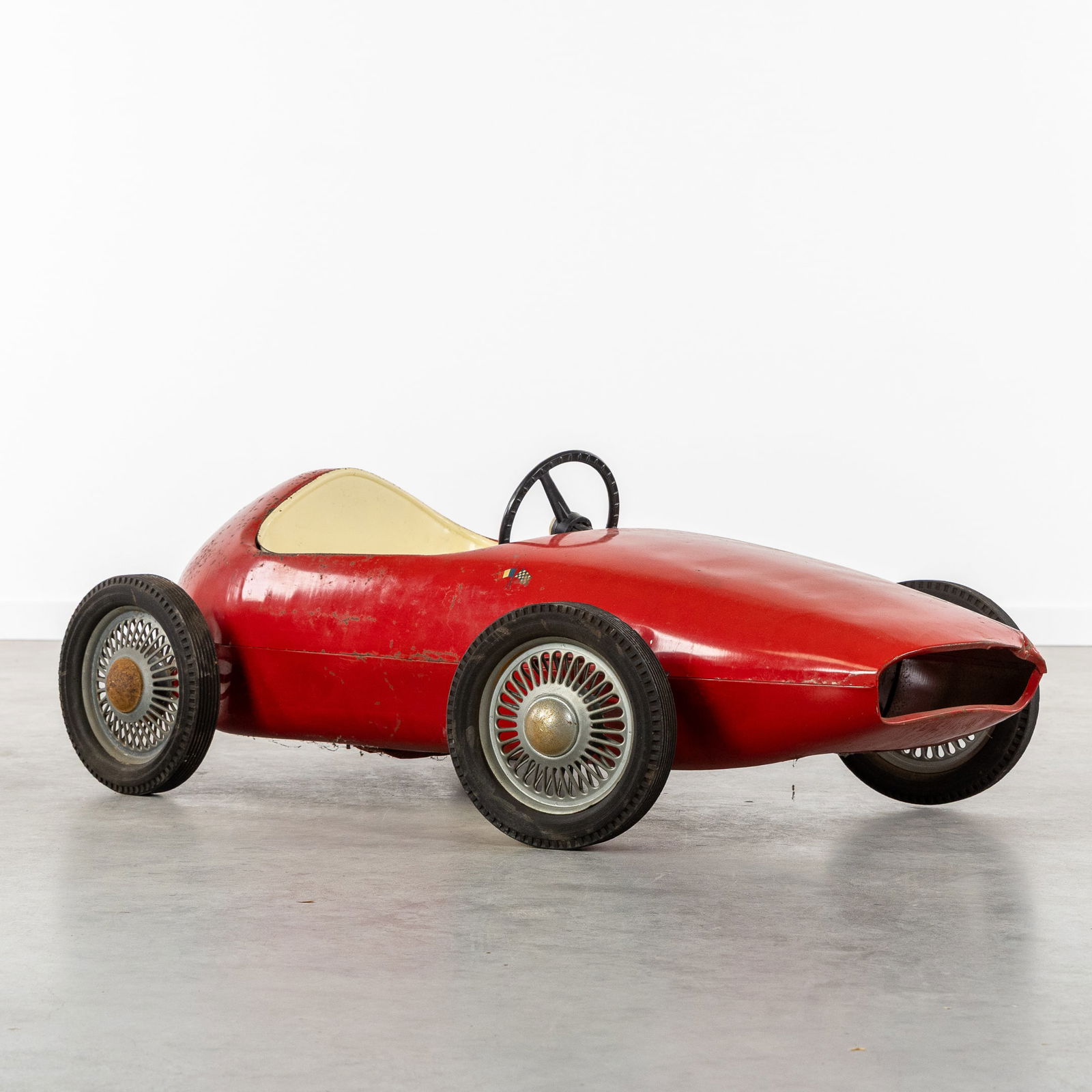 A Vintage Ferrari Children's Pedal Car, Patinated metal, circa 1960.: A Vintage Ferrari Children's Pedal Car, Patinated metal, circa 1960. Red and white patinated steel.Hard rubber tires and a plastic steering wheel.Circa 1960.