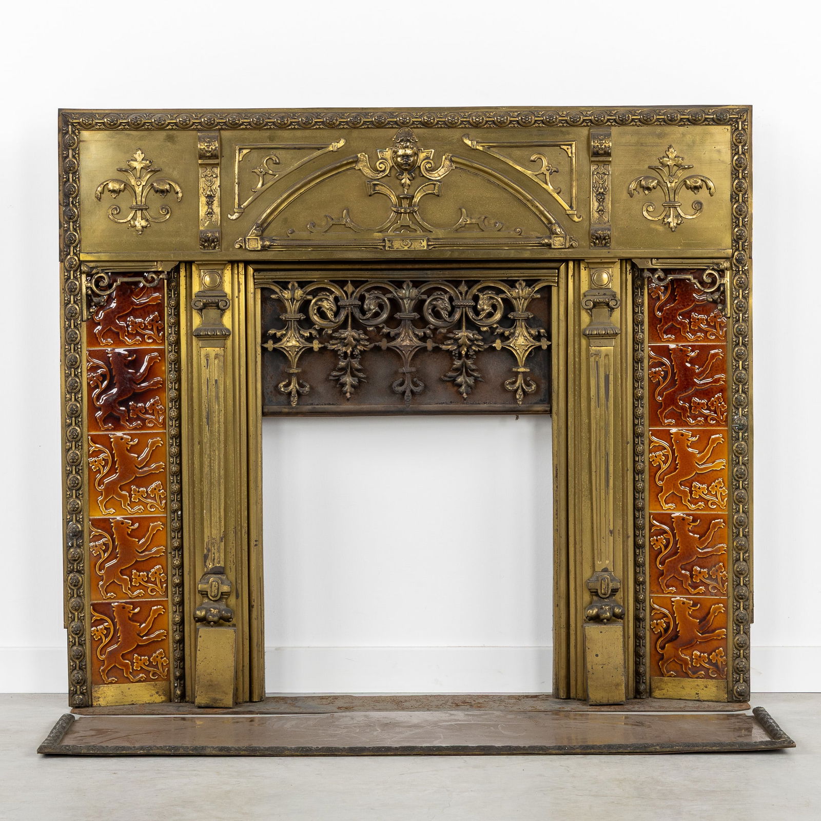 An Antique Fireplace Insert, Renaissance Style, Brass, Bronze and Ceramic.: An Antique Fireplace Insert, Renaissance Style, Brass, Bronze and Ceramic. Brass and bronze, finished with ceramic tiles.Fireplace insert, fireplace surround.Decorated with a child's head, ribbed mold