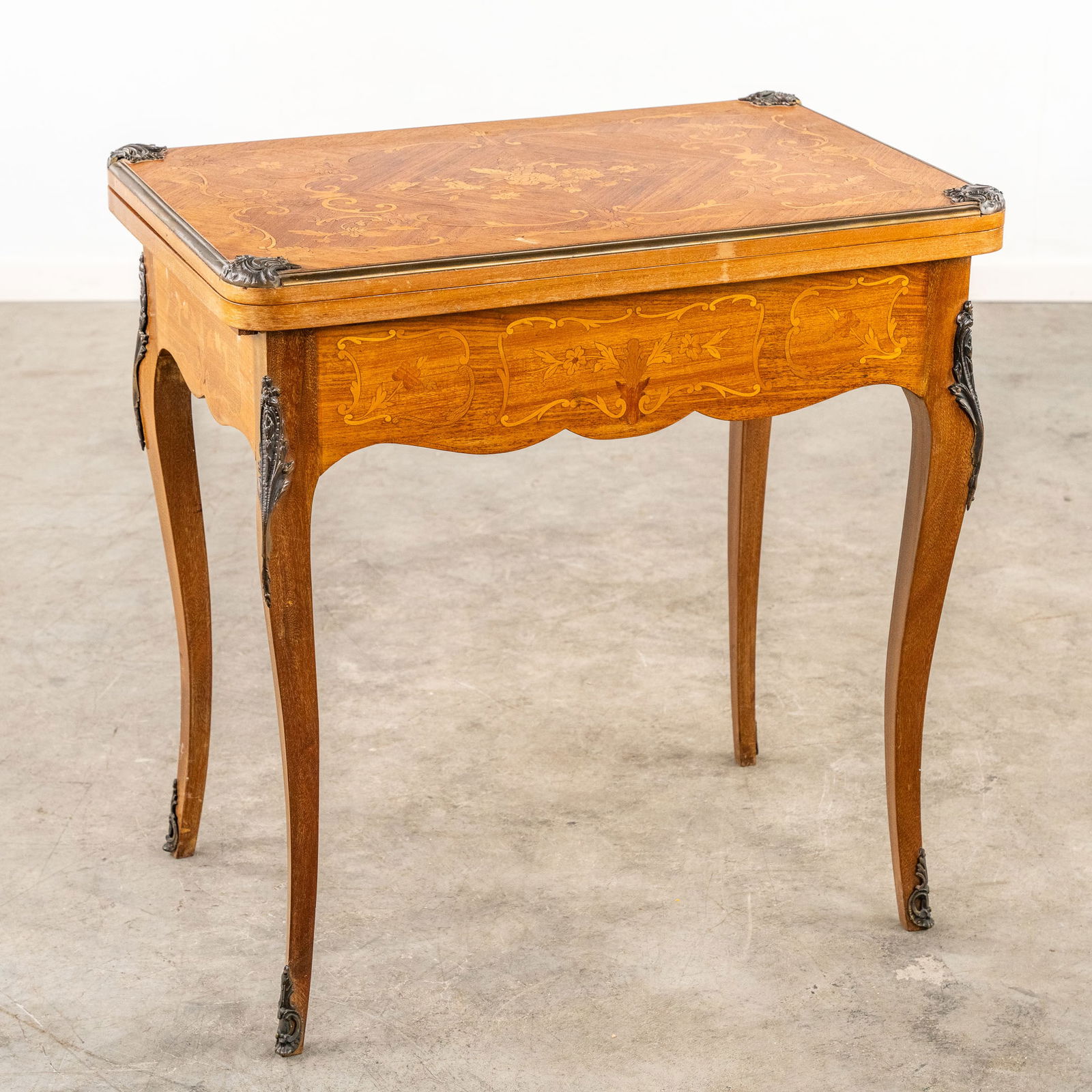 A game table, finished with marquetry inlay. Louis XV style, Circa 1950.: A game table finished with marquetry inlay. Circa 1950. Finished with a floral decor and mounted with bronze. Louis XV style. 