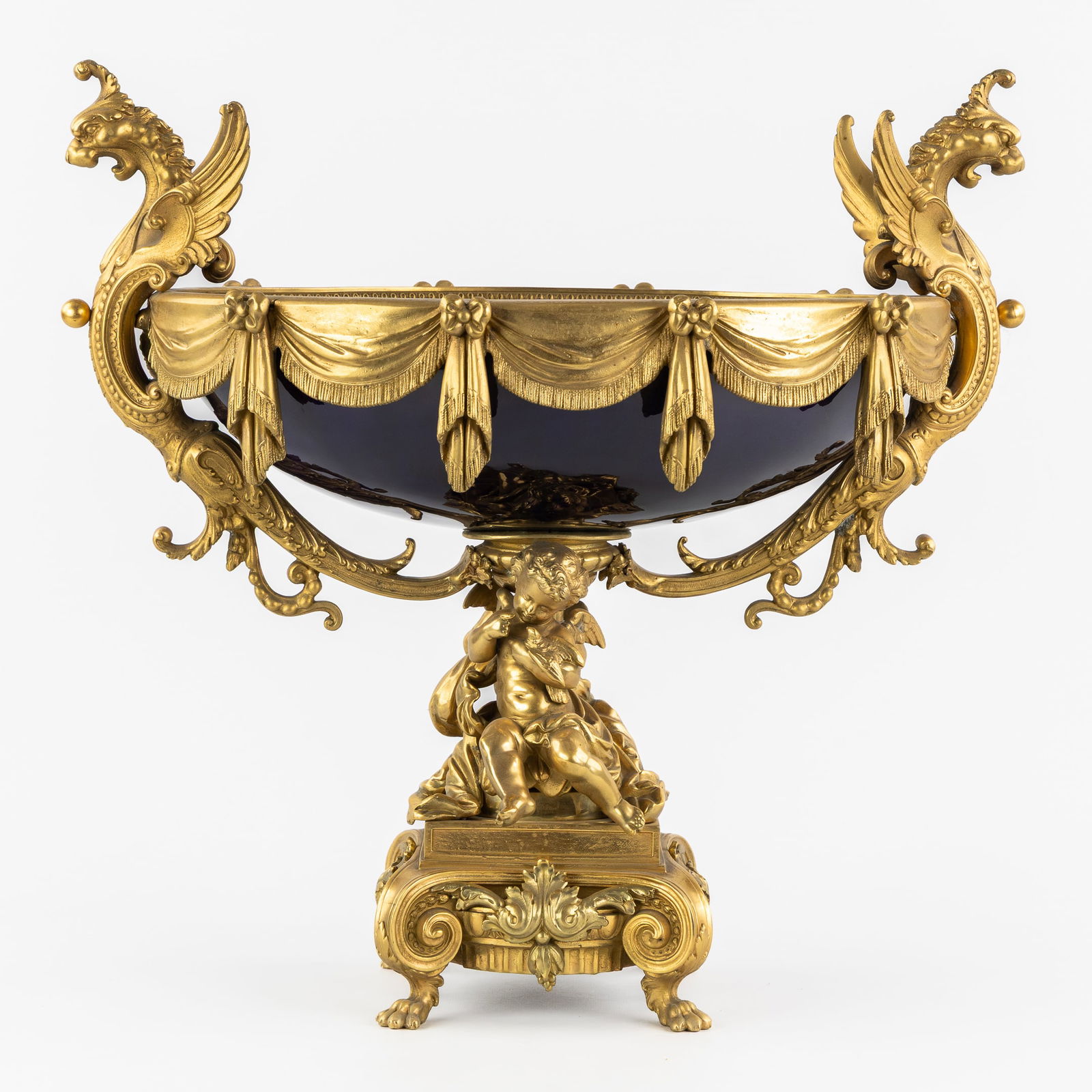 A large 'Milieu de Table' or Centerpiece, Gilt bronze and cobalt blue stoneware. Putti and Griffins.: A large 'Milieu de Table' or Centerpiece, Gilt bronze and cobalt blue stoneware. Putti and Griffins. France, circa 1900. Gilt bronze in a rich Renaissance style, decorated with garlands and 'Curtain V