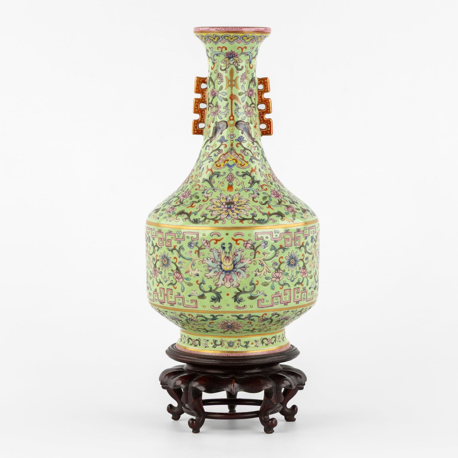 A Chinese Famille Rose Vase, with floral decorations on a lime-green ground, Qianlong marked.: A Chinese Famille Rose Vase, with floral decorations on a lime-green ground, Qianlong marked. Chinese porcelain, Famille Rose.Mounted on a wooden stand. Height including the stand: 37,