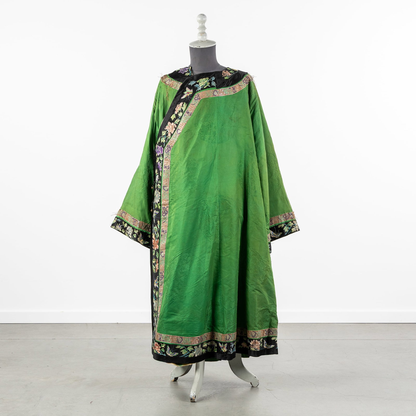 A Chinese Green ground Embroidered Silk Robe, Changyi, Late Qing Dynasty, circa 1900.: A Chinese Green ground Embroidered Silk Robe, Changyi, Late Qing Dynasty, circa 1900. Silk and fabric. Interior finished with fur. Decorated with embroidered butterflies, birds and flowers. (160 x 130