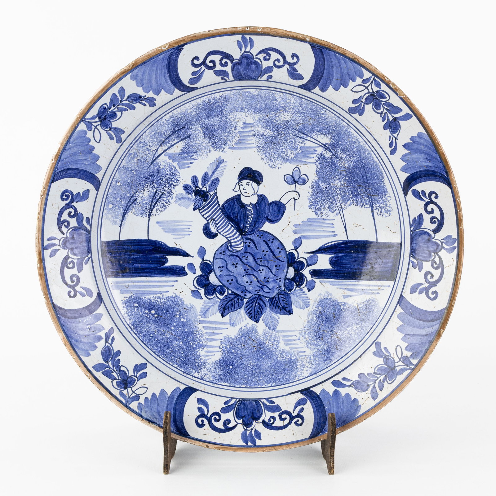 An Antique Blue and White Plate, decorated with a Woman and a Cornucopia, Delftware, 18th C.: An Antique Blue and White Plate, decorated with a Woman and a Cornucopia, Delftware, 18th century. Delftware.Decorated with a woman holding a cornucopia. Rim decorated with floral motifs.Marked 'TP'
