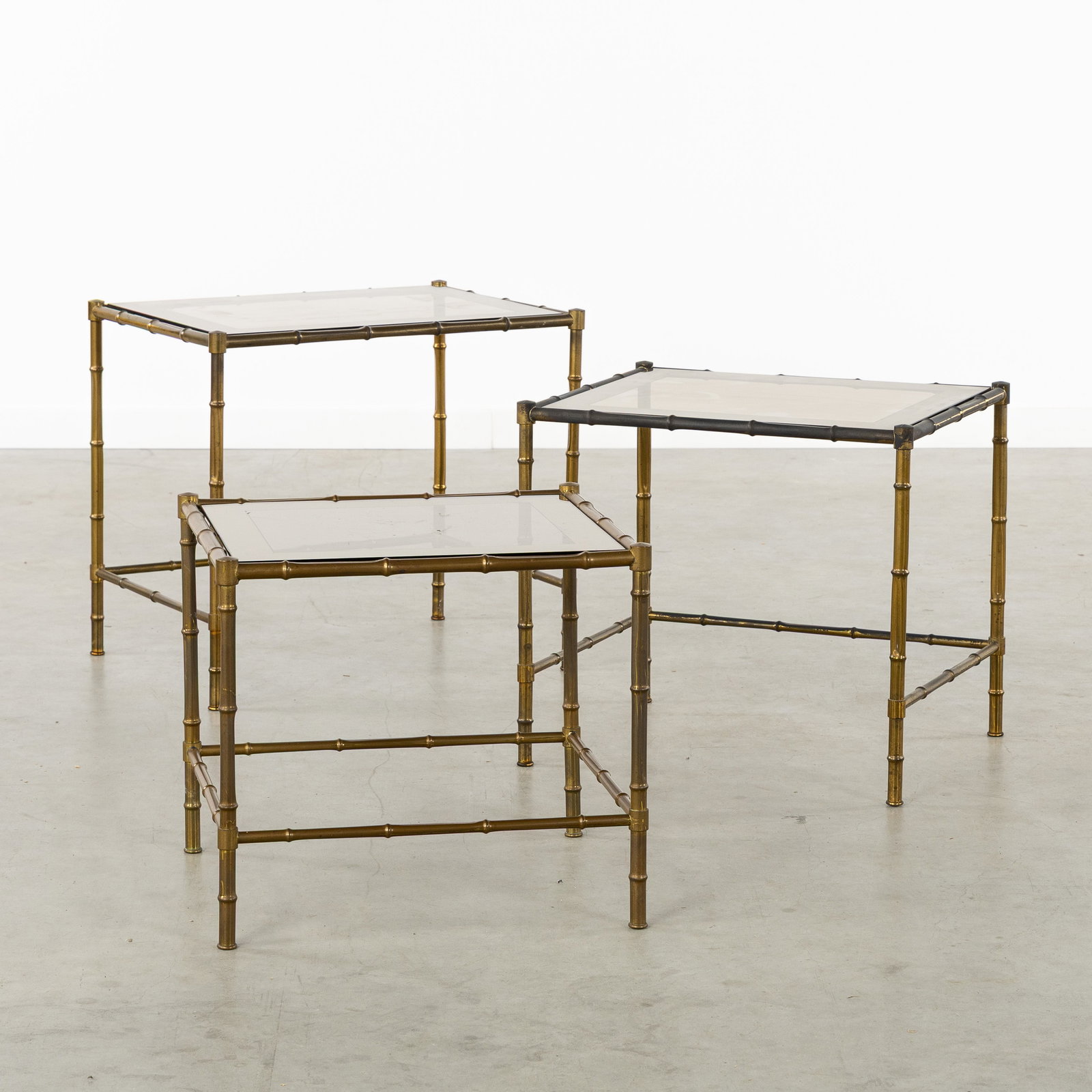 A Set of Three Nesting Tables, faux bamboo, brass and glass, in the style of Maison Baguès. Circa: A Set of Three Nesting Tables, faux bamboo, brass and glass, in the style of Maison Baguès. Circa 1960. Brass and glass.Three rectangular nesting side tables.Glass tops with mirrored edges.