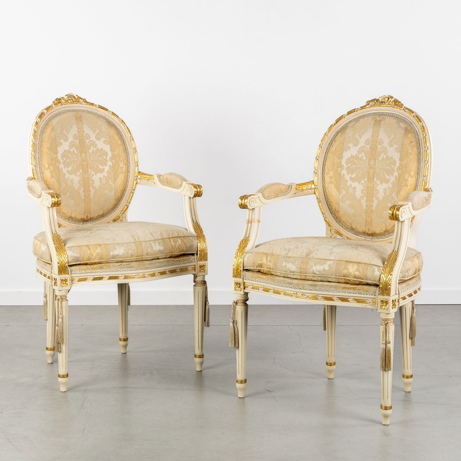 A Pair of Louis XVI-style armchairs, Sculptured and patinated wood, Silk upholstery.: A Pair of Louis XVI-style armchairs, Sculptured and patinated wood, Silk upholstery. Sculptured, patinated, and gilded wood.Upholstered in silk.Decorated with a bow, acanthus leaves, and fluted legs
