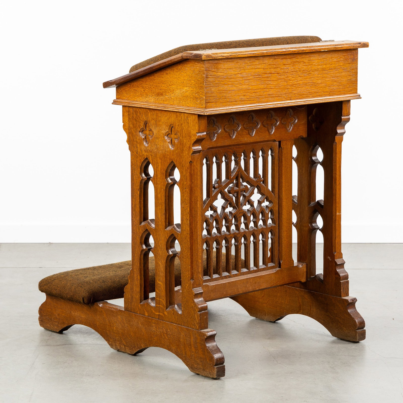 A Gothic Revival Prayer Bench. Openwork sculptures and upholstered in brown fabric. (1 of 9)