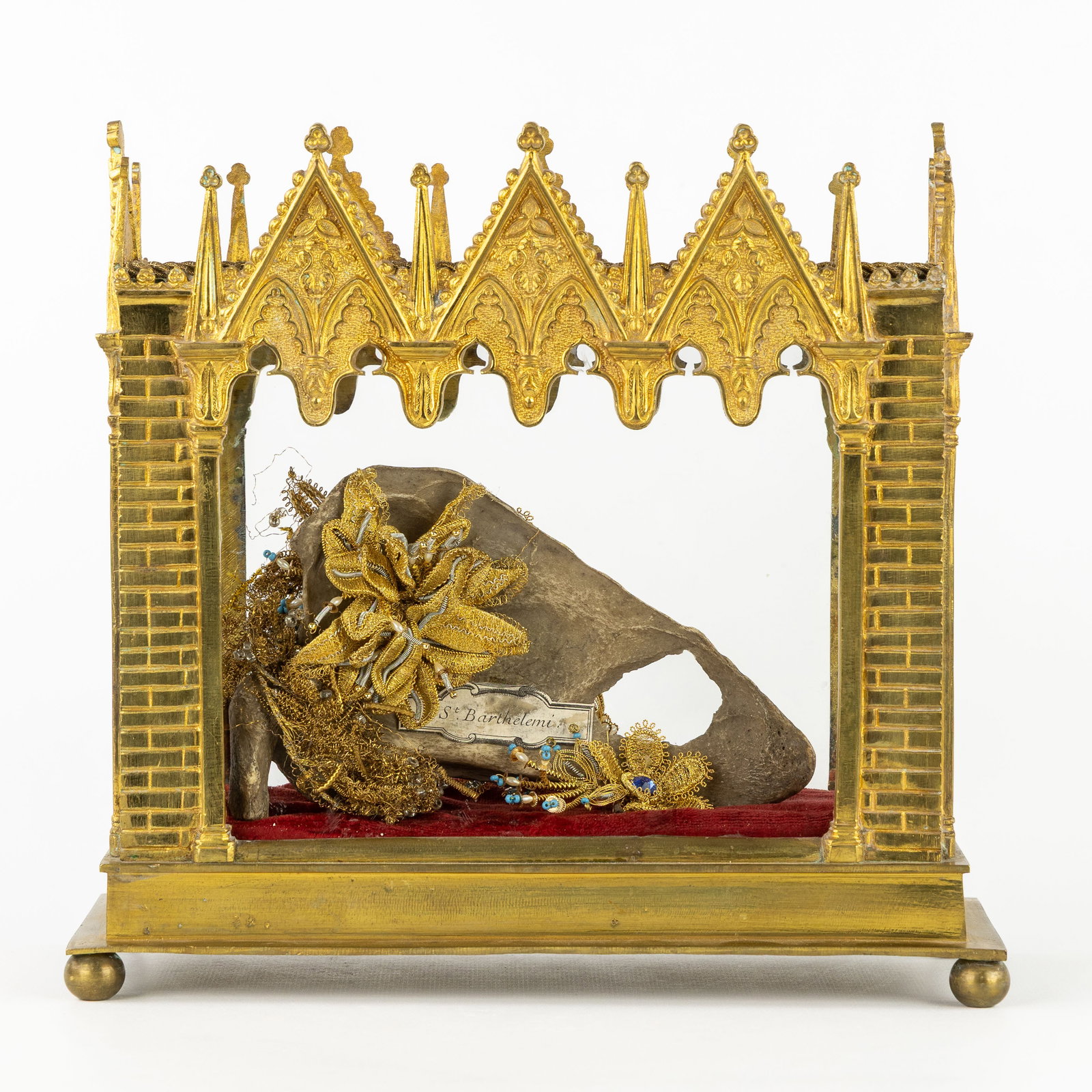 A Gothic Revival reliquary shrine with a large bone relic of Saint Bartholomew.: A Gothic Revival reliquary shrine with a large bone relic of Saint Bartholomew. Gothic Revival architectural reliquary shrine, gilded brass, decorated with filigree flowers. From the bones of Saint Ba