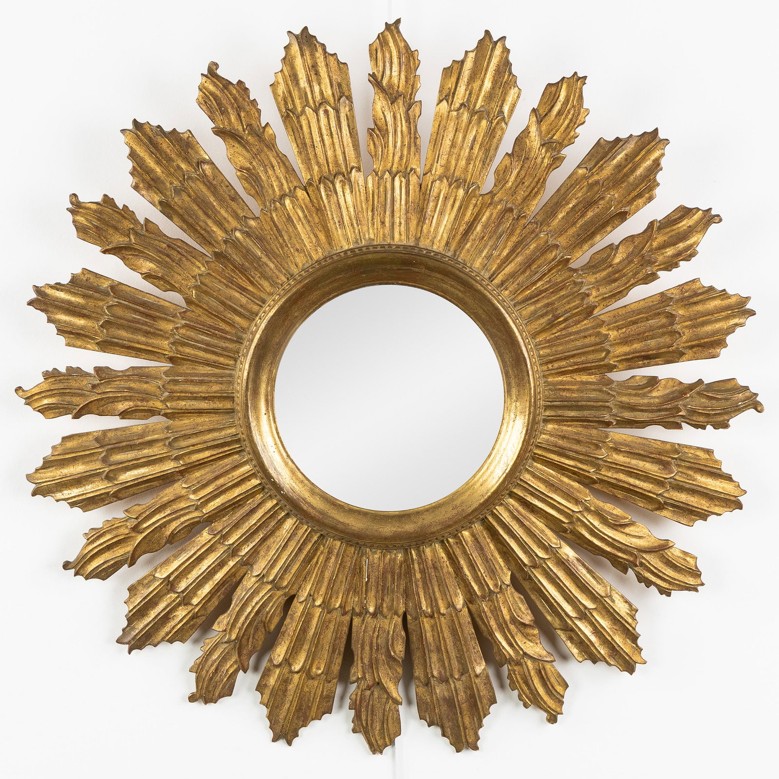 A Large Mid-Century sunburst mirror, gilded and wood-sculptured, Convex Glass. Circa 1970.: A Large Mid-Century sunburst mirror, gilded and wood-sculptured, Convex Glass. Circa 1970. Convex glass.Gilded wood.Circa 1970. Dimensions: (W:70 cm) The absence of a condition report does not imply a