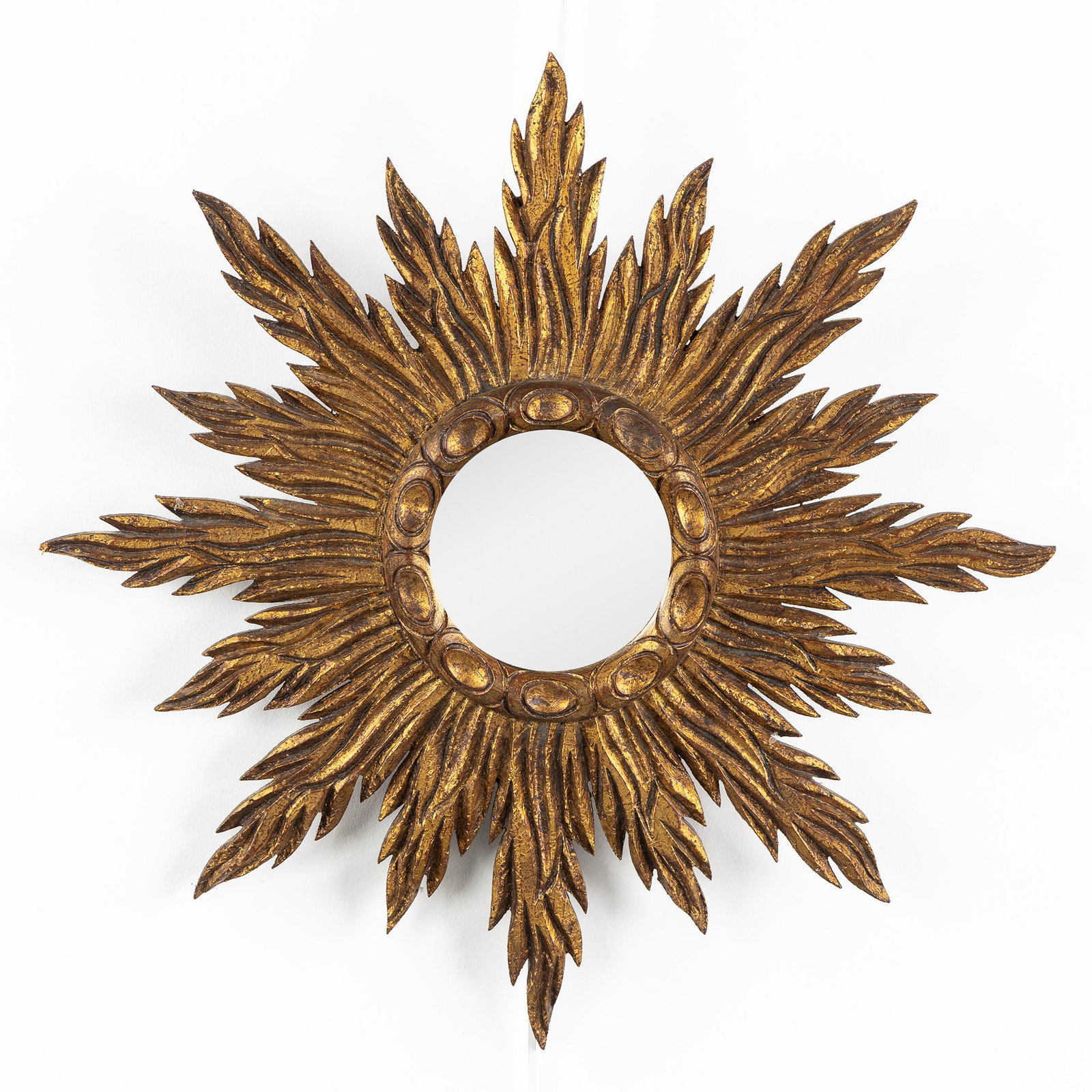 A Mid-Century sunburst mirror, gilt and sculptured wood, Glass. Circa 1970.: A Mid-Century sunburst mirror, gilt and sculptured wood, Glass. Circa 1970. Glass.Gilded wood.Circa 1970. Dimensions: (W:52 cm) The absence of a condition report does not imply a perfect item. Please 