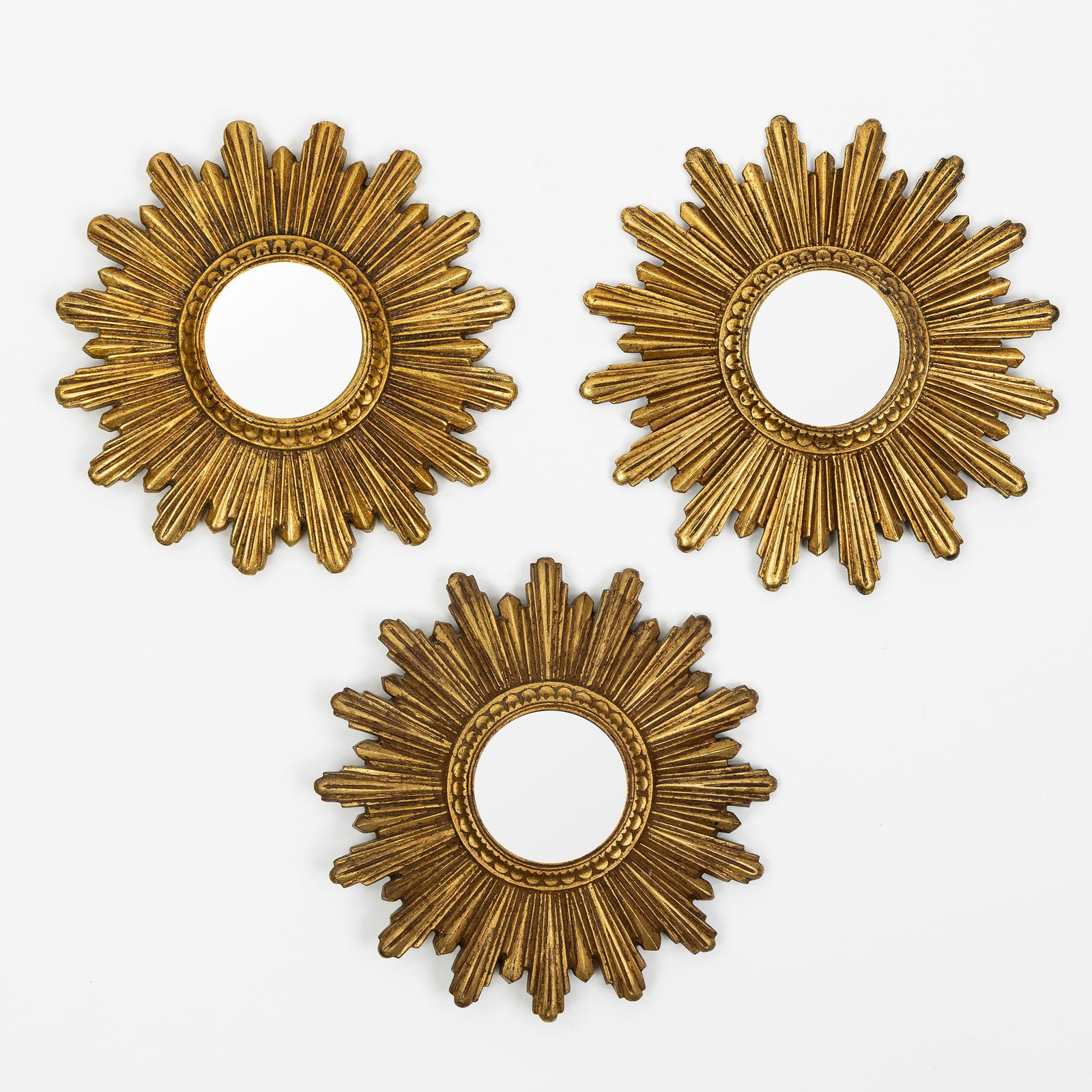 A Set of three small Mid-Century sunburst mirrors, gilded, Convex Glass. Circa 1970.: A Set of three small Mid-Century sunburst mirrors, gilded, Convex Glass. Circa 1970. Convex glass.Gilded resin.Circa 1970. D: 24,5 cm / D: 24,5 cm / D: 26 cm. Dimensions: (W:26 cm) The absence of a co
