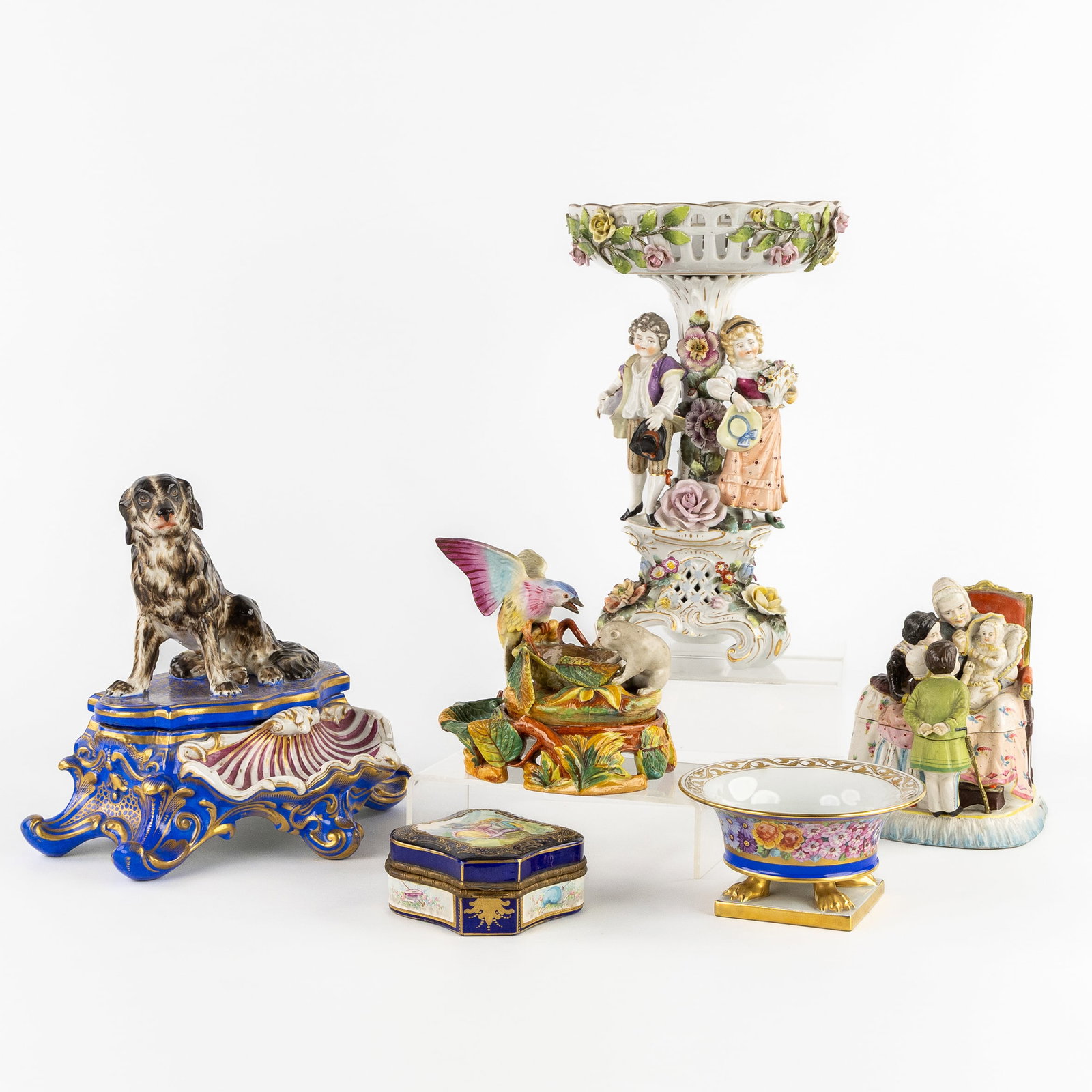 Six objects, Tazza, Inkwell, Vide Poche and a small box. Polychrome porcelain. France, Germany,: Six objects, Tazza, Inkwell, Vide Poche and a small box. Polychrome porcelain. France, Germany, Hungary, 19th and 20th C. A bowl on a pedestal, richly decorated with a young boy and girl. Floral decor