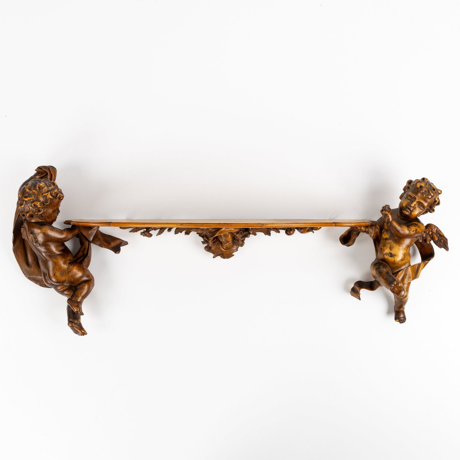 A wall-mounted console, wood-sculpted in Baroque style. Circa 1900.: A wall-mounted console, wood-sculpted in Baroque style. Circa 1900. Finished with putti/angels and banners. Centrally with a shelf. Dimensions: (W:33 x H:94 cm) Condition: Missing pieces.