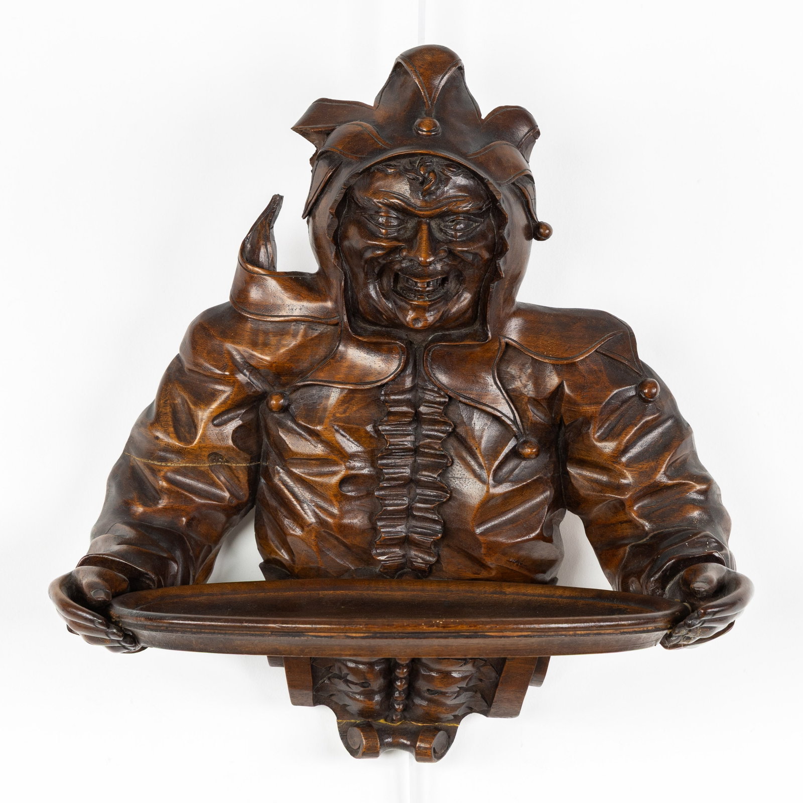 A Wood-sculptured vide poche or wall shelf, in the shape of a jester or harlequin, Black Forest, (1 of 7)