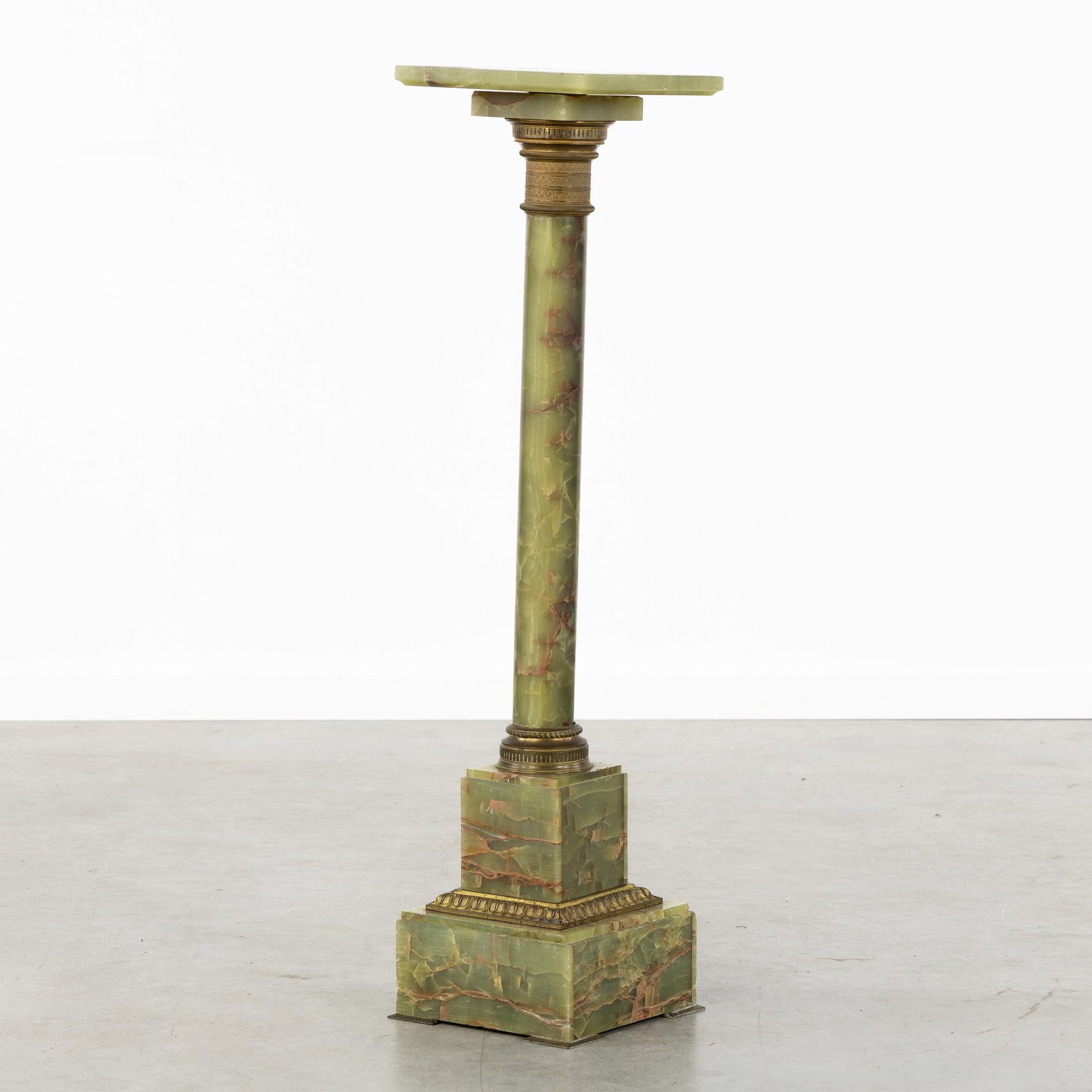 An Onyx console or pedestal with a rotating platform and bronze fittings, 19th/20th C.: An Onyx console or pedestal with a rotating platform and bronze fittings, 19th/20th century. Green onyx, finished with bronze fittings.Platform dimensions: 25 x 25 cm. Dimensions: (W:25 x H:101,5 x L: