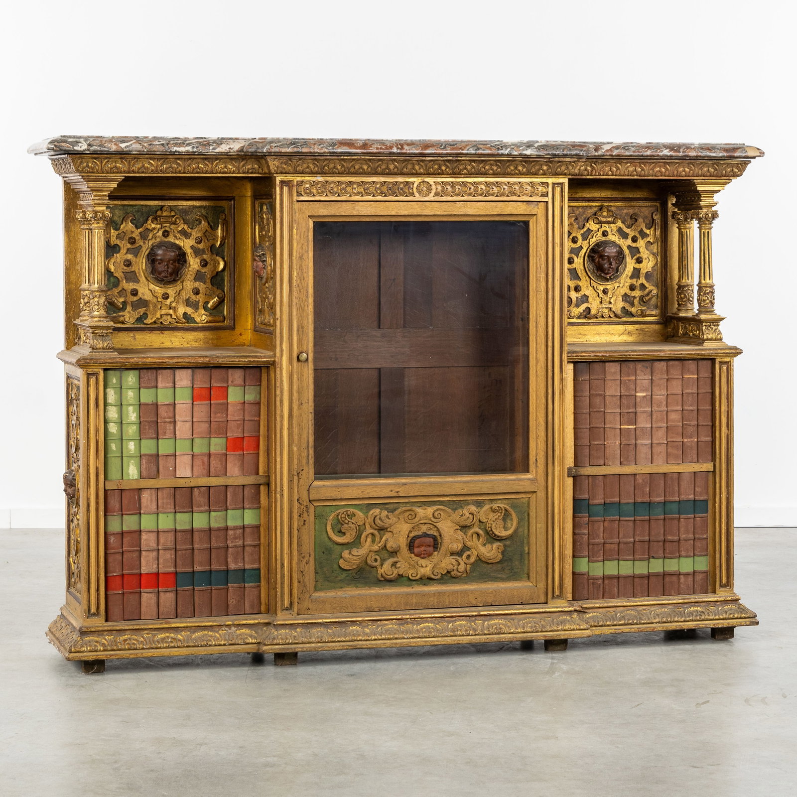 A Special cabinet with faux book decoration and putti, sculptured and patinated wood, Renaissance: A Special cabinet with faux book decoration and putti, sculptured and patinated wood, Renaissance Revival, Italy, 19th century. Sculptured and patinated wood, with gilded finish.Cabinet or bookcase, w