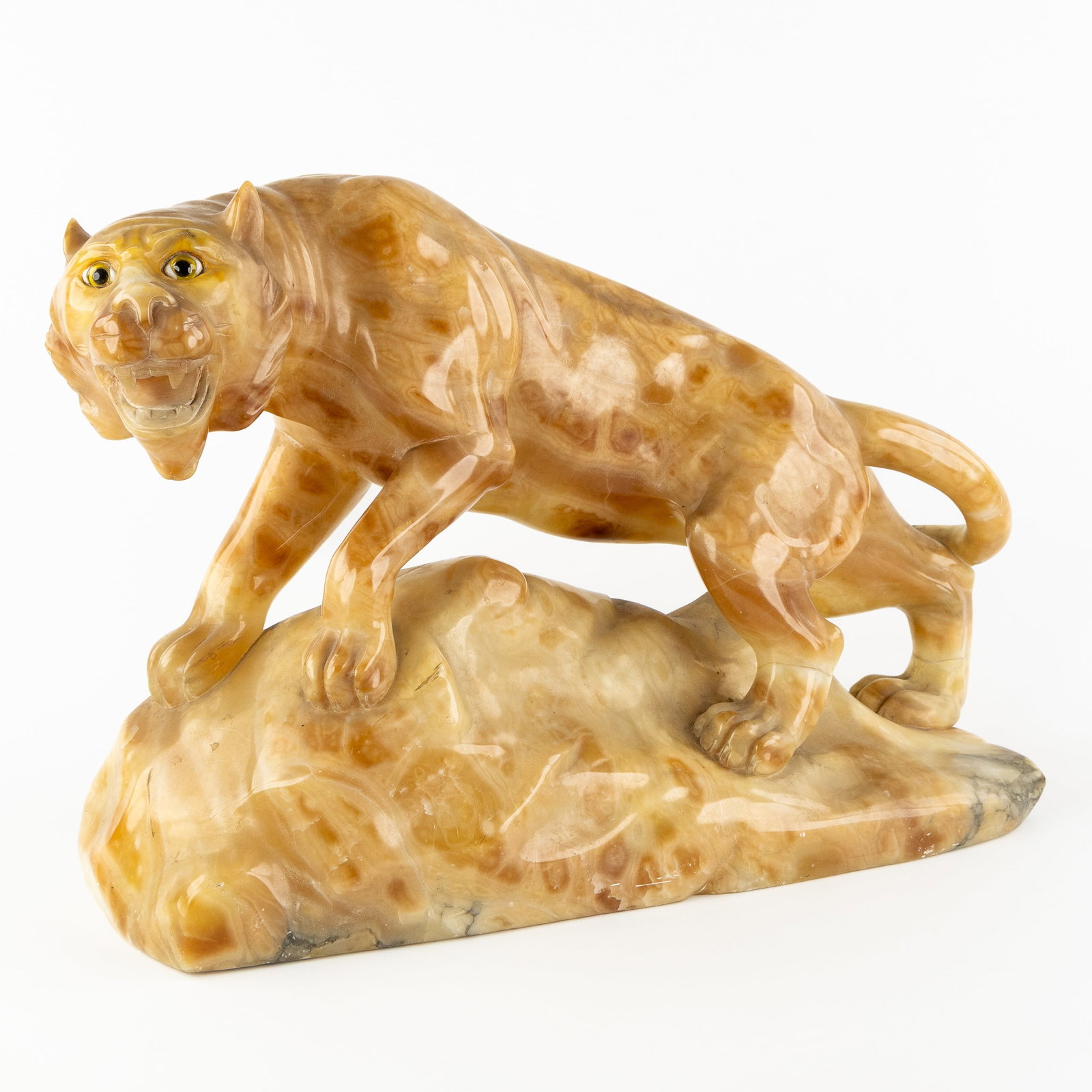 An Alabaster sculpture of a Lioness, Art Deco, circa 1940.: An Alabaster sculpture of a Lioness, Art Deco, circa 1940. Sculptured yellow alabaster, finished with glass eyes.Unsigned.Art Deco, circa 1940. Dimensions: (W:51 x H:34 x L:20 cm) The absence of a con