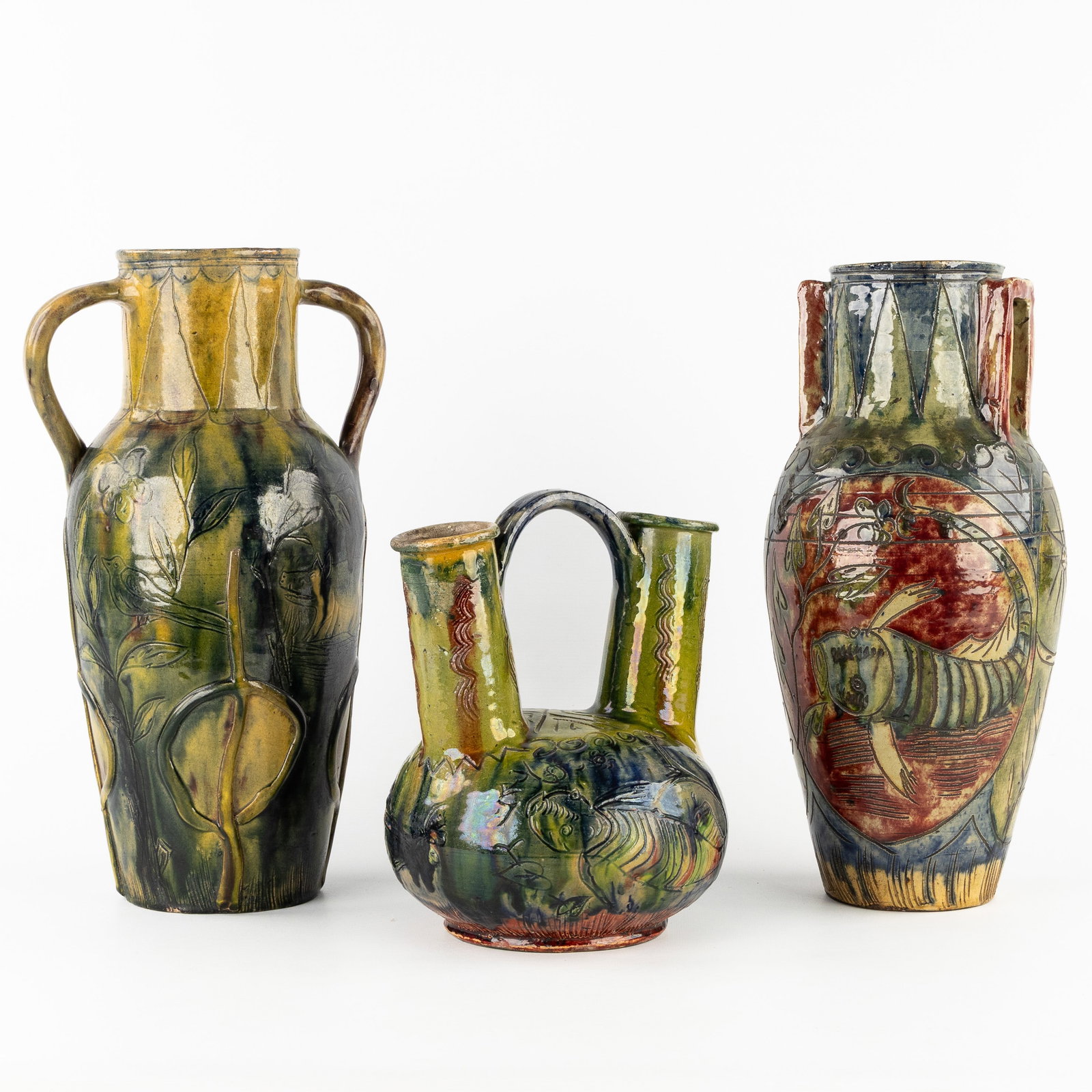 Bredene earthenware, three decorative vases. Early 20th century.: Bredene earthenware, three decorative vases. Early 20th century.Flemish pottery. Vase with two openings, floral decoration with insects and fish.25 x 21 x 18 cm. Vase with two handles, decoratio