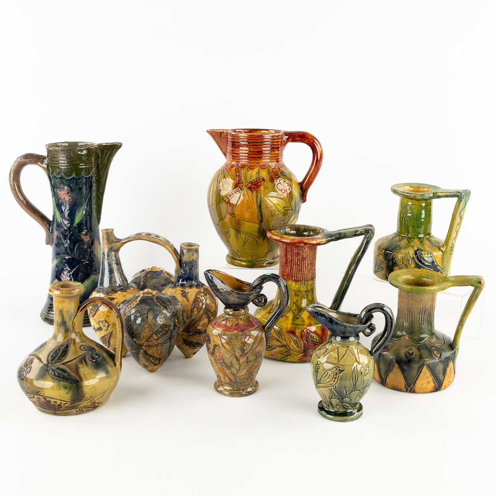 Bredens Aardewerk, Negen schenkkannen en vaasjes. Begin 20ste eeuw.: Bredens Aardewerk, Negen schenkkannen en vaasjes. Begin 20ste eeuw. Een collectie van 9 stuks schenkkannen, vazen en pic-fleurs. Bredene, Vlaams Aardewerk. Finished with the typical 