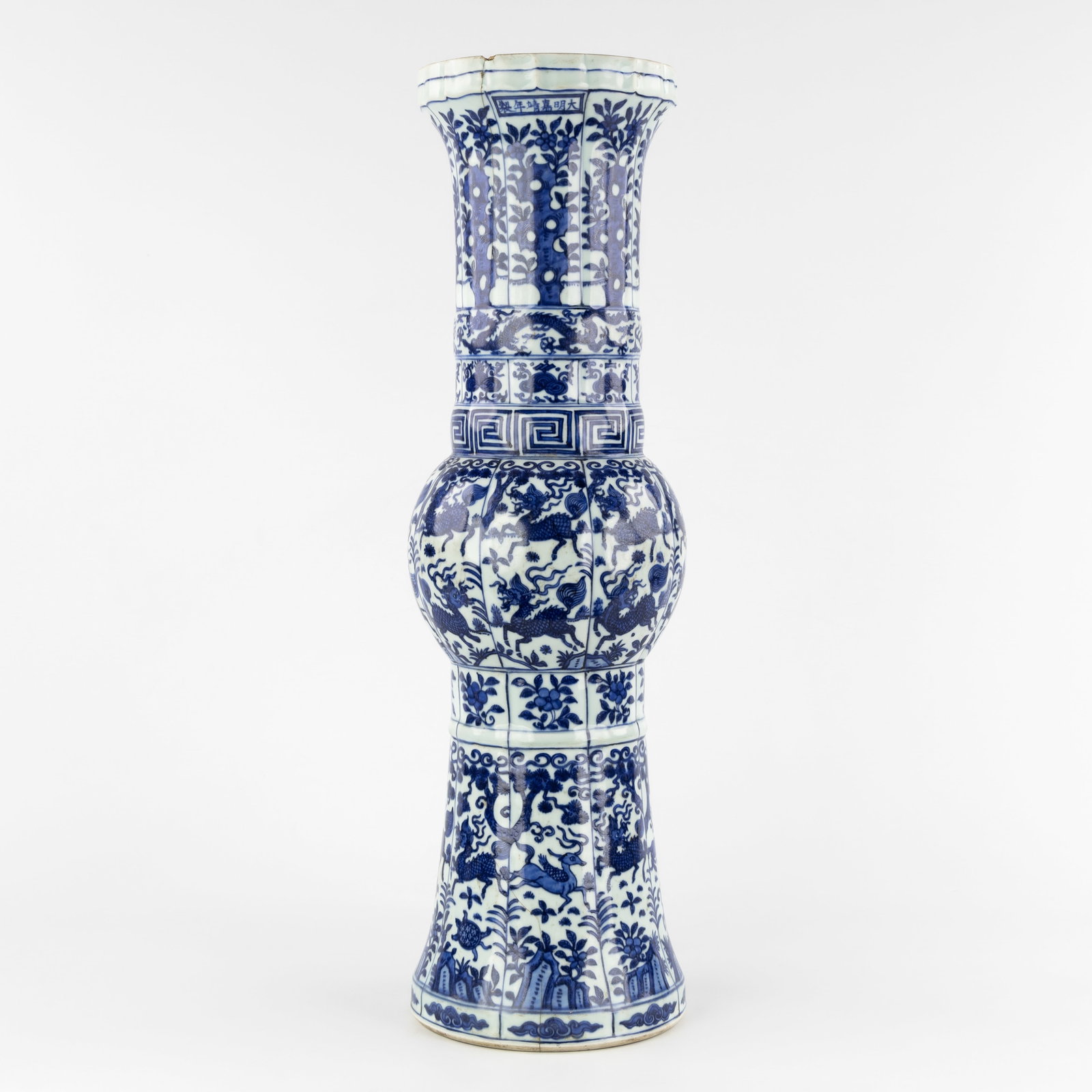 A large Chinese lobed 'Gu' vase, blue-white, dragons and foo dogs, Jiajing mark. 18th-19th C.: A large Chinese lobed 'Gu' vase, blue-white, dragons and foo dogs, Jiajing mark. 18th-19th century. Lobed vase, decorated with blossoms, dragons, deer, and mythological figures. Marked Jiajing n