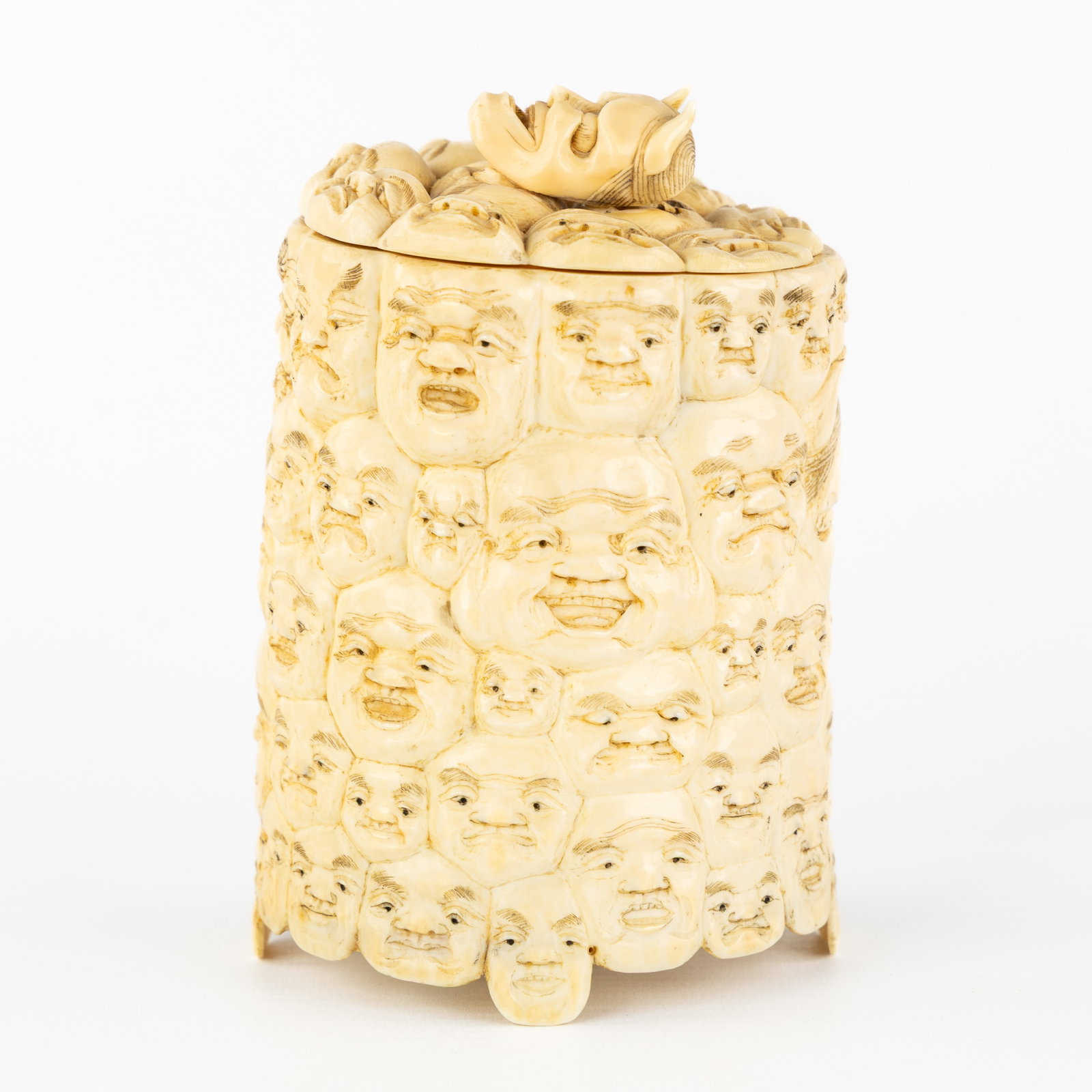 A Japanese '100 Faces' covered jar, Sculptured ivory, Meiji, circa 1900.: A Japanese '100 Faces' covered jar, Sculptured ivory, Meiji, circa 1900. Sculptured ivory.Covered jar or brush pot decorated with '100 Faces' decor or finely carved Kabuki masks.Japan, Meiji, circa 19