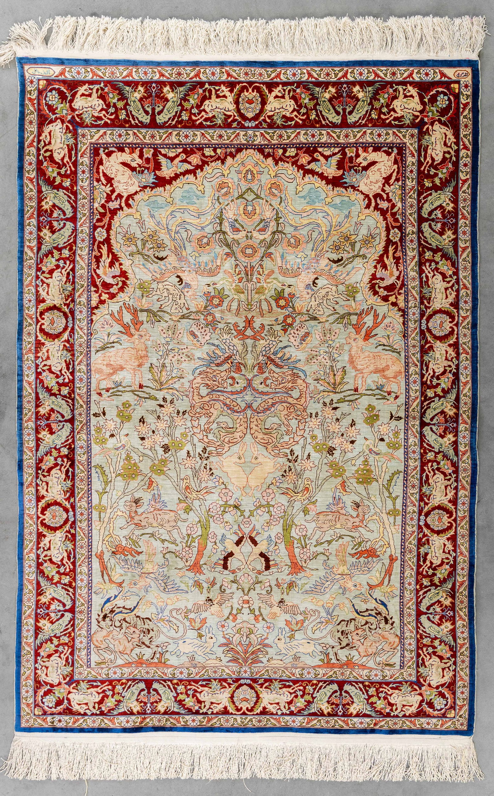 An Oriental figurative handmade carpet, Silk, Hereke, Turkiye (149 x 102 cm).: An Oriental figurative handmade carpet, Silk, Hereke, Turkiye (149 x 102 cm). Signed. Dimensions: (W:102 x H:149 cm) The absence of a condition report does not imply a perfect item. Please send us an 