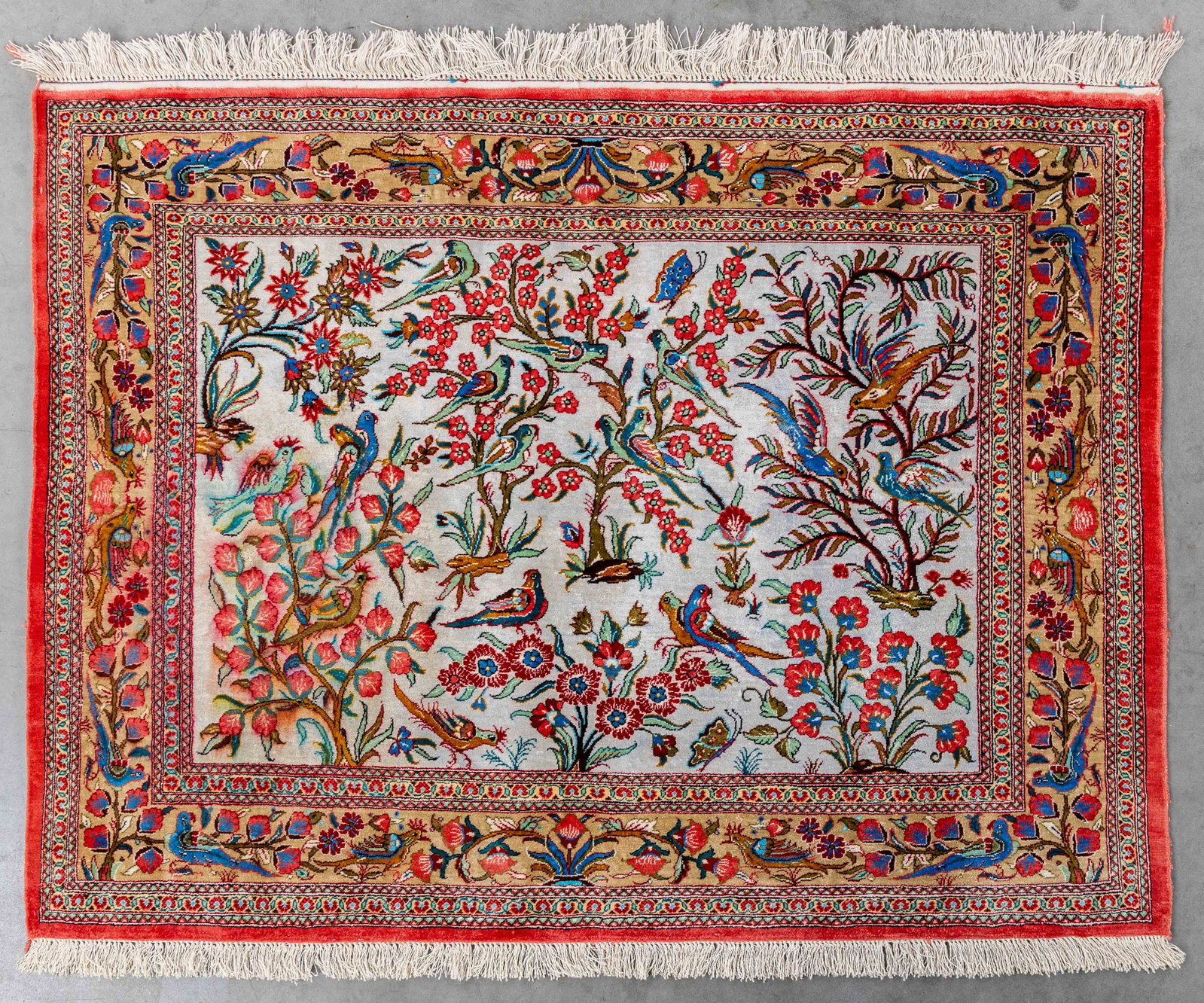 An Oriental handmade figurative carpet with bird decoration, Silk, Ghoum, Iran (107 x 81 cm).: An Oriental handmade figurative carpet with bird decoration, Silk, Ghoum, Iran (107 x 81 cm). Dimensions: (W:81 x H:107 cm) The absence of a condition report does not imply a perfect item. Please send