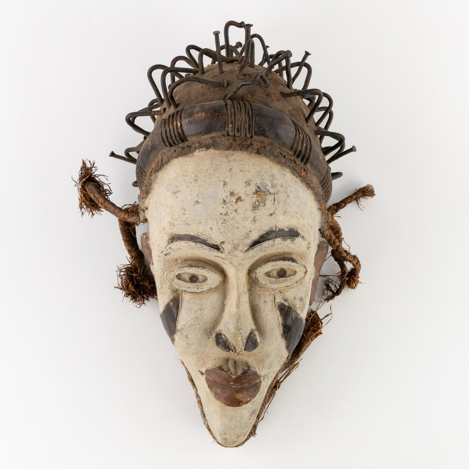 A Decorative Central African mask, sculptured wood, metal, and raffia, 20th C. (1 of 7)