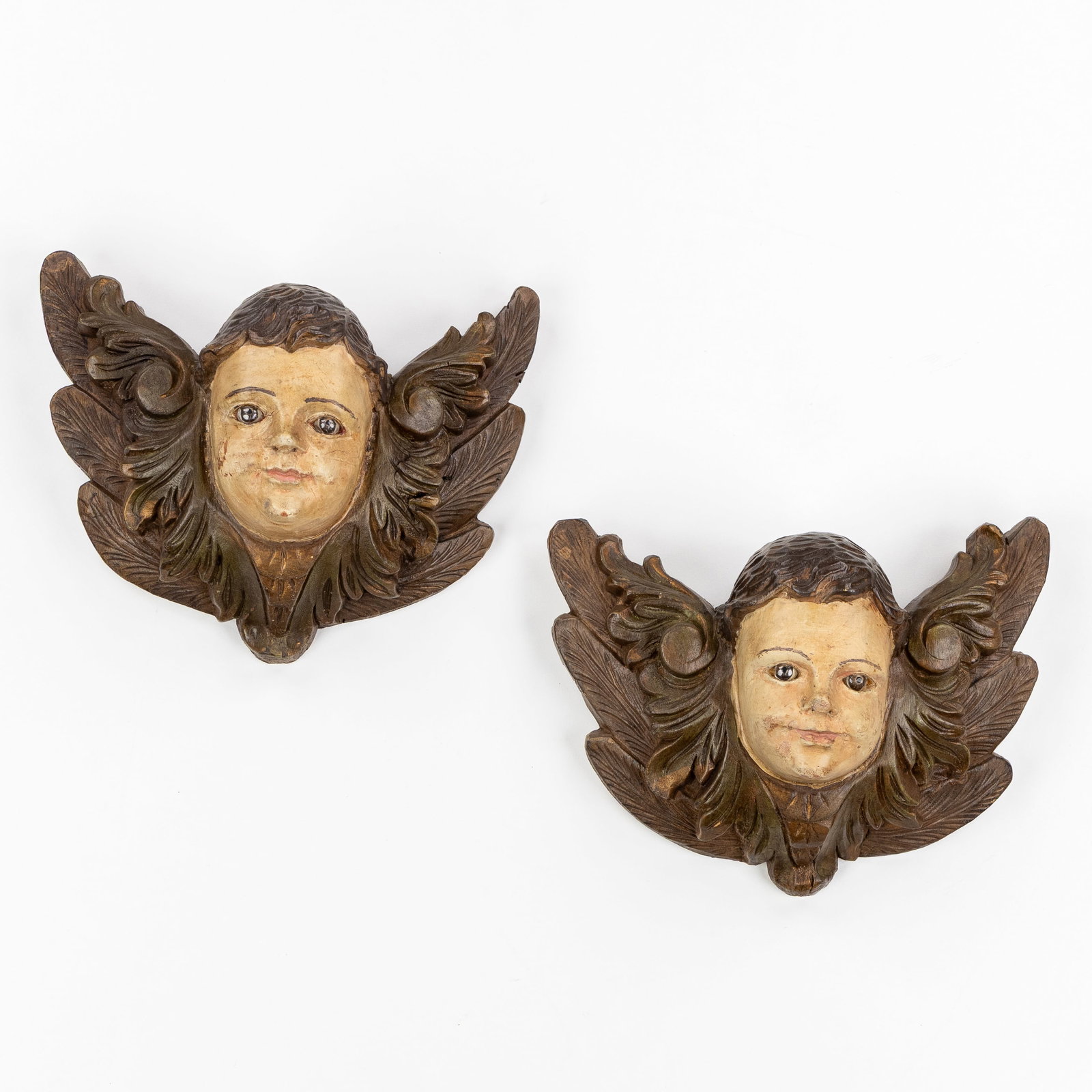 A Pair of wood-sculptured angels with glass eyes, Baroque style, 20th: A Pair of wood-sculptured angels with glass eyes, Baroque style, 20th century. Patinated and sculpted wood. (29 x 22 x 11 cm)