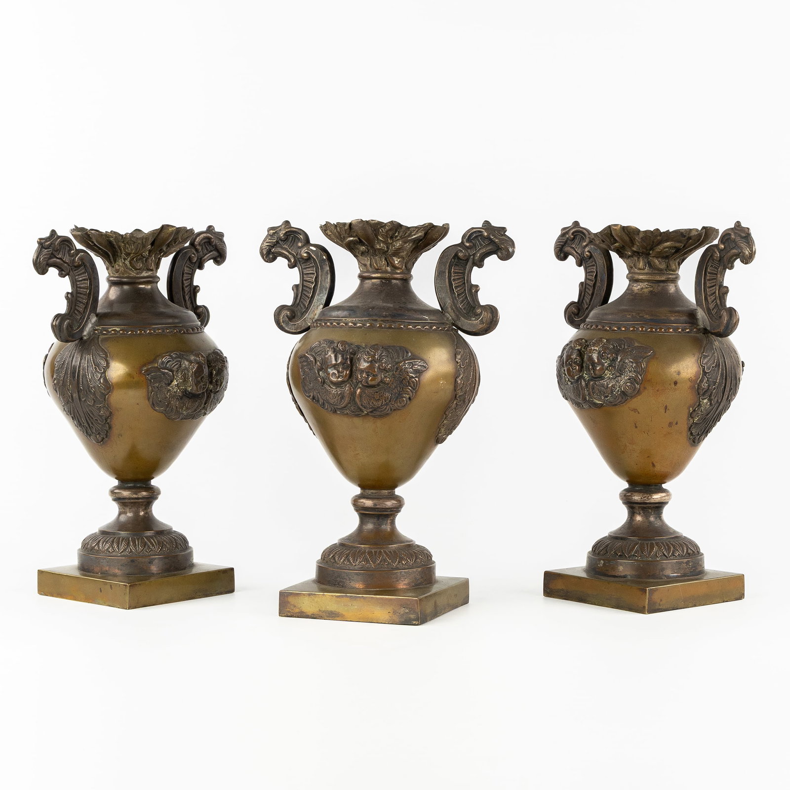 A Set of three decorative vases or urns, brass and copper, decorated with cherub heads. (1 of 11)