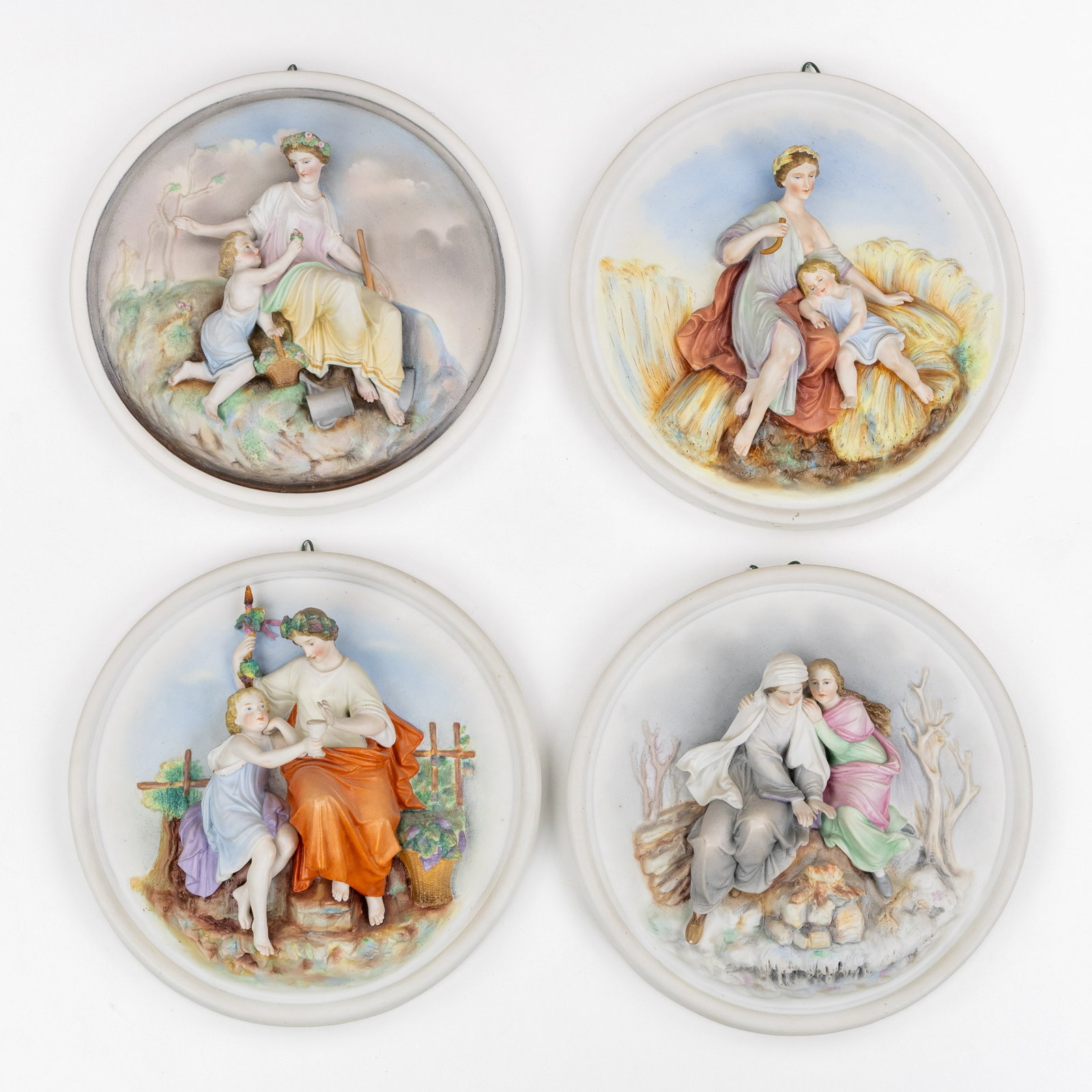 'The Four Seasons', a set of four biscuit porcelain plaques, Germany, circa 1900.: 'The Four Seasons', a set of four biscuit porcelain plaques, Germany, circa 1900. Polychrome biscuit porcelain.Four plaques or round wall sculptures with an allegorical representation of the four seas