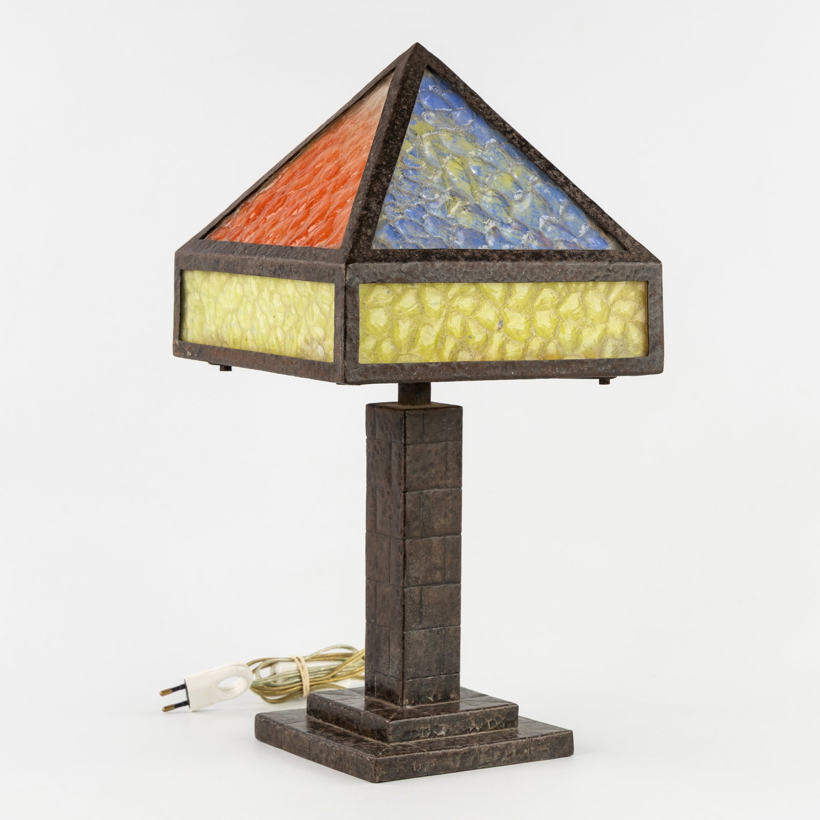 An Arts & Crafts table lamp, hammered wrought iron and coloured glass.: An Arts & Crafts table lamp, hammered wrought iron and coloured glass. Hammered wrought iron and coloured/painted glass.In the style of W.B. Brown, United States. (23 x 46 x 23 cm)