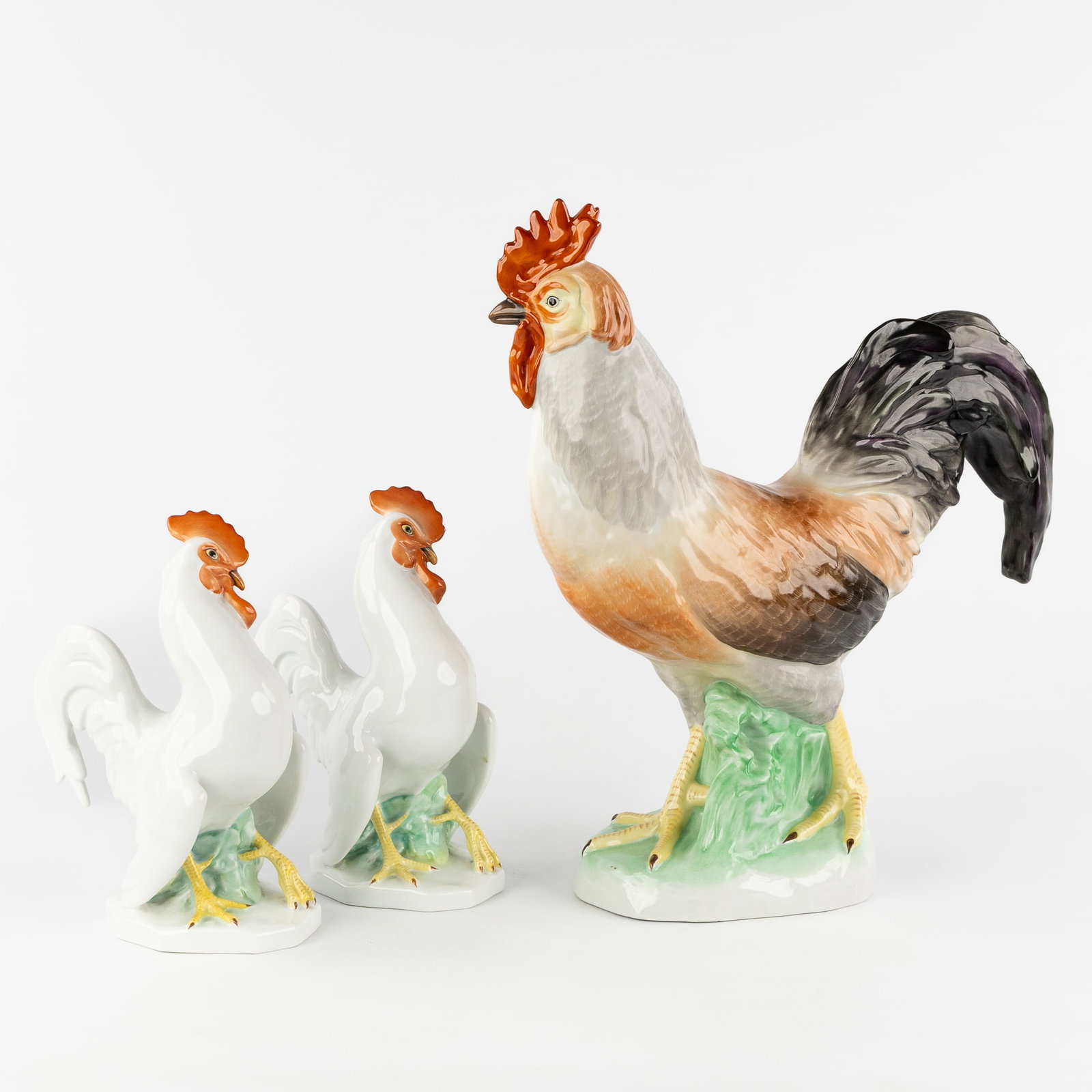 Herend, a Rooster and two Cockerels, polychrome hand-painted porcelain, Hungary, second half of the: Herend, a Rooster and two Cockerels, polychrome hand-painted porcelain, Hungary, second half of the 20th century. Polychrome porcelain.A large rooster (H: 39,5 cm) and two cockerels (H: 23 cm).Hand-