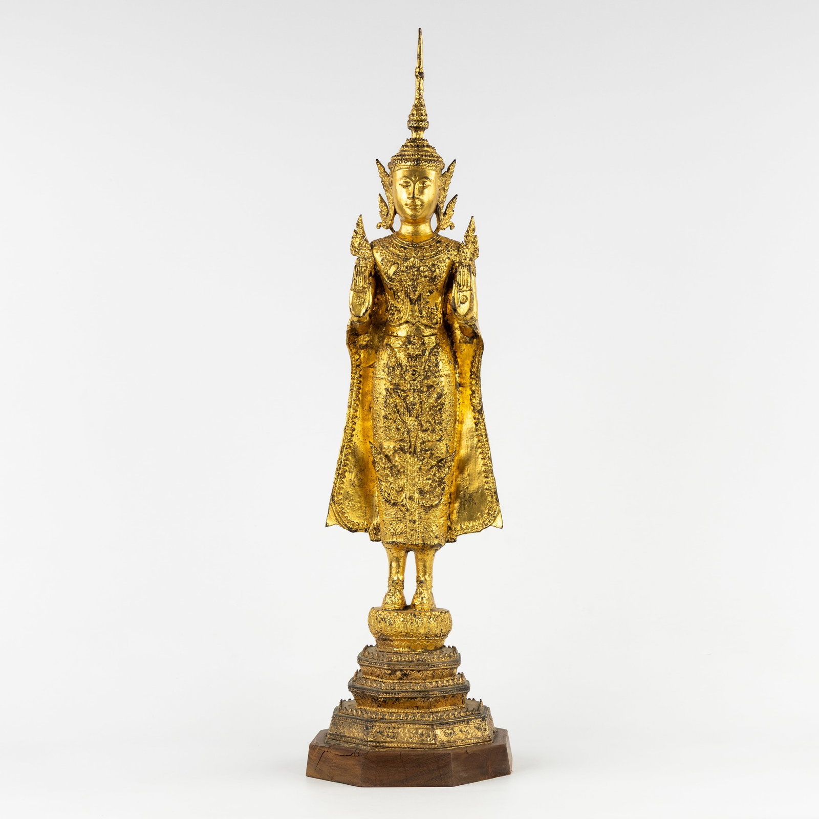 A Thai Rattanakosin Buddha, Abhaya mudra, gilded bronze.: A Thai Rattanakosin Buddha, Abhaya mudra, gilded bronze. Gilded bronze.Standing Buddha or bodhisattva, in abhaya mudra posture (protection and courage).Mounted on a wooden base.Rattakosin